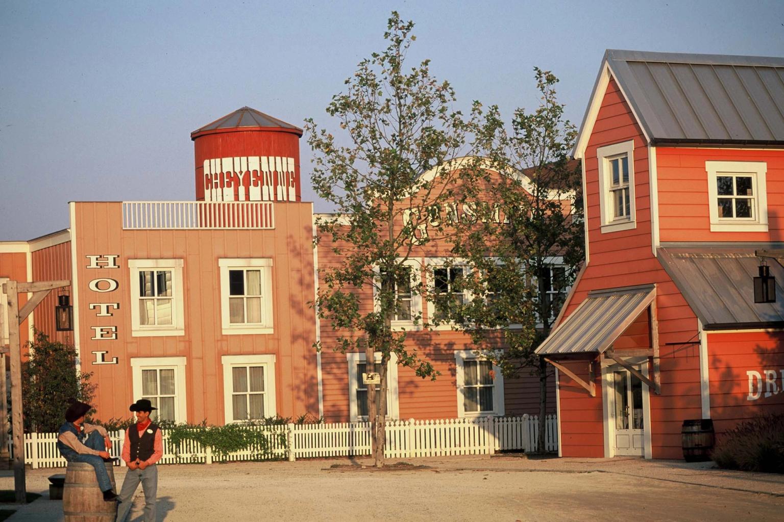 två cowboys står framför en rad byggnader i en västernstad