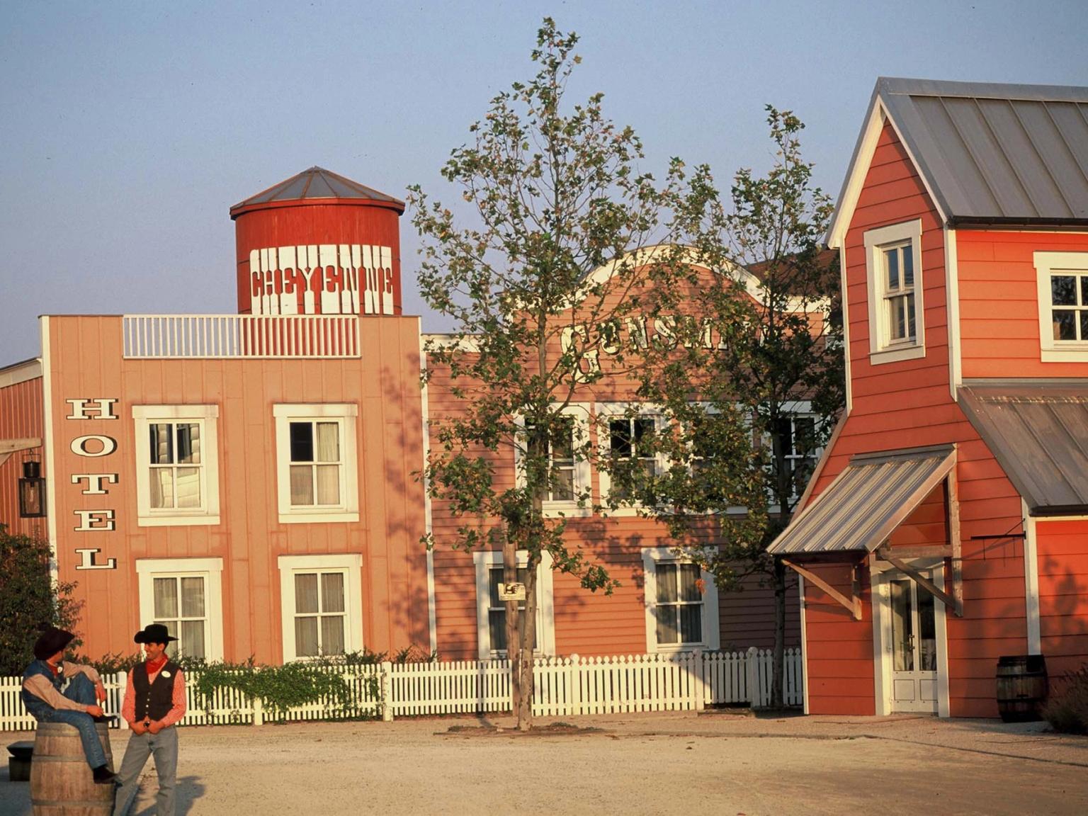 två cowboys står framför en rad byggnader i en västernstad