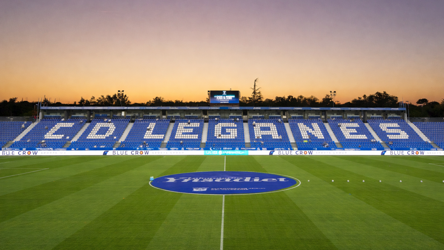 Estadio de fútbol al atardecer con "C.D. LEGANES" escrito en asientos blancos en las gradas azules sobre el césped verde.
