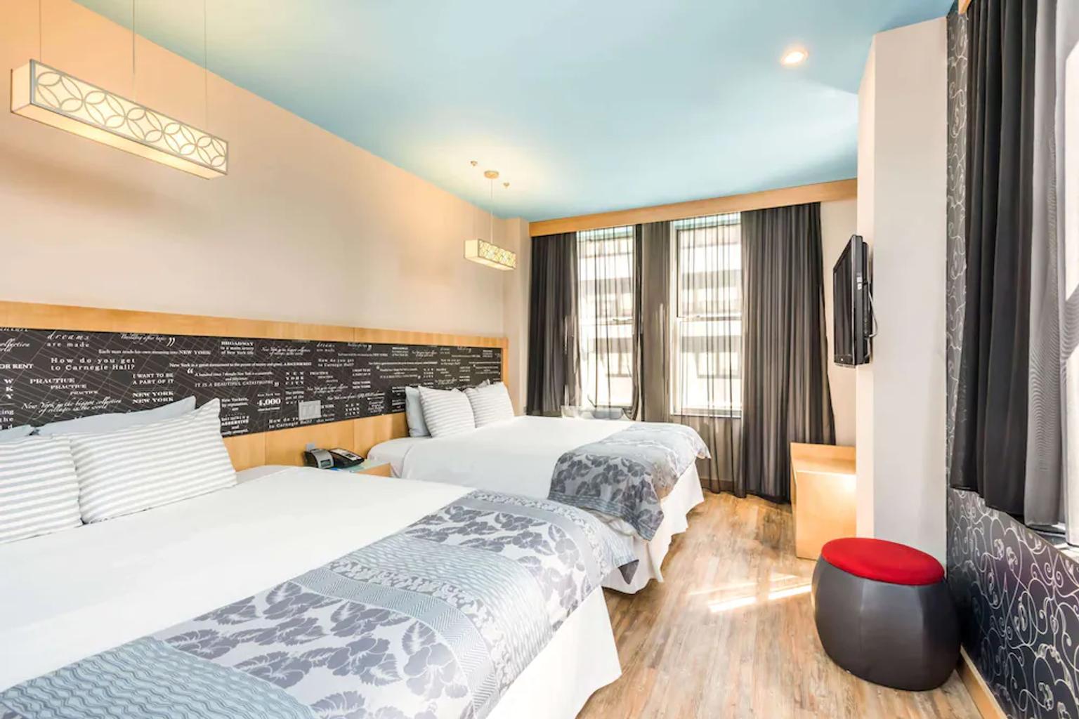 et hotellrom med to senger og en fjernsyn
