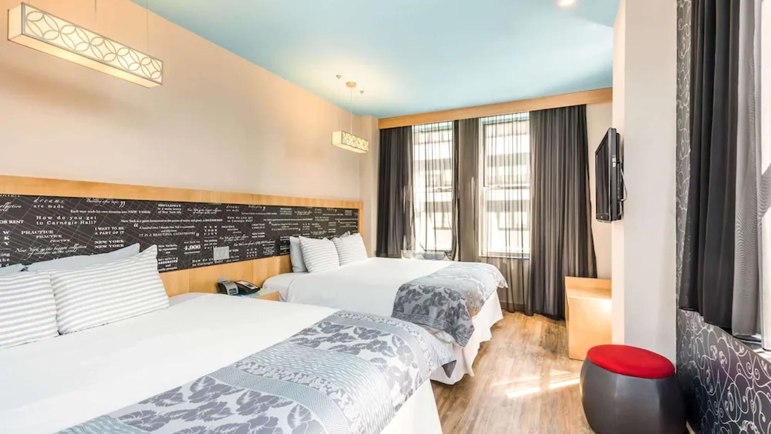 et hotellrom med to senger og en fjernsyn