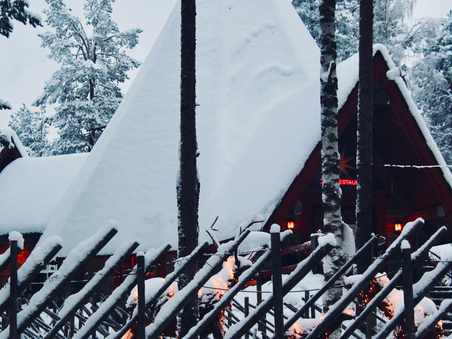 ett trästaket framför ett snötäckt hus