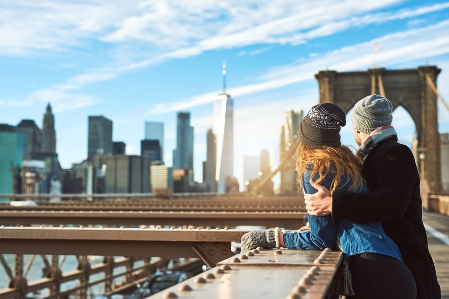 een man en een vrouw staan op een brug en kijken naar de skyline van de stad.