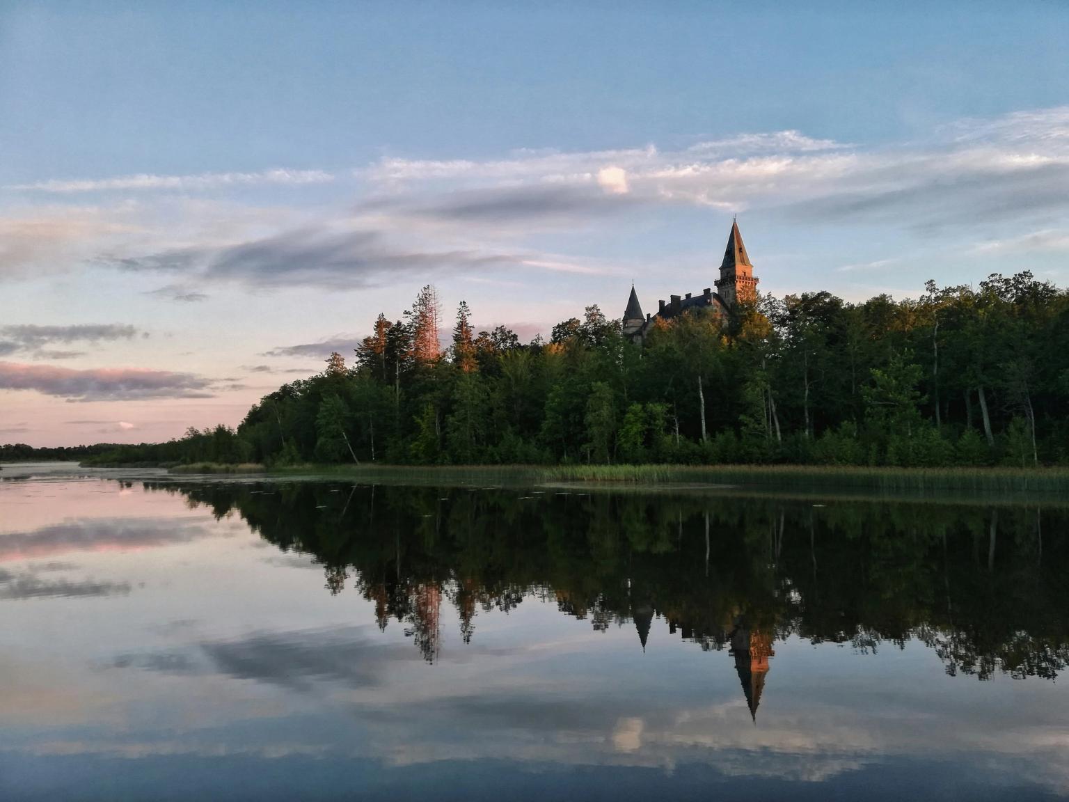 a castle is reflected in the water of a lake surrounded by trees
