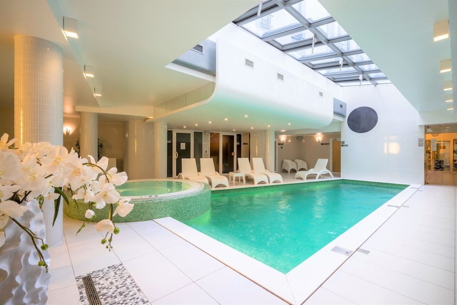 en stor inomhus simbassäng med stolar och blommor i ett spa