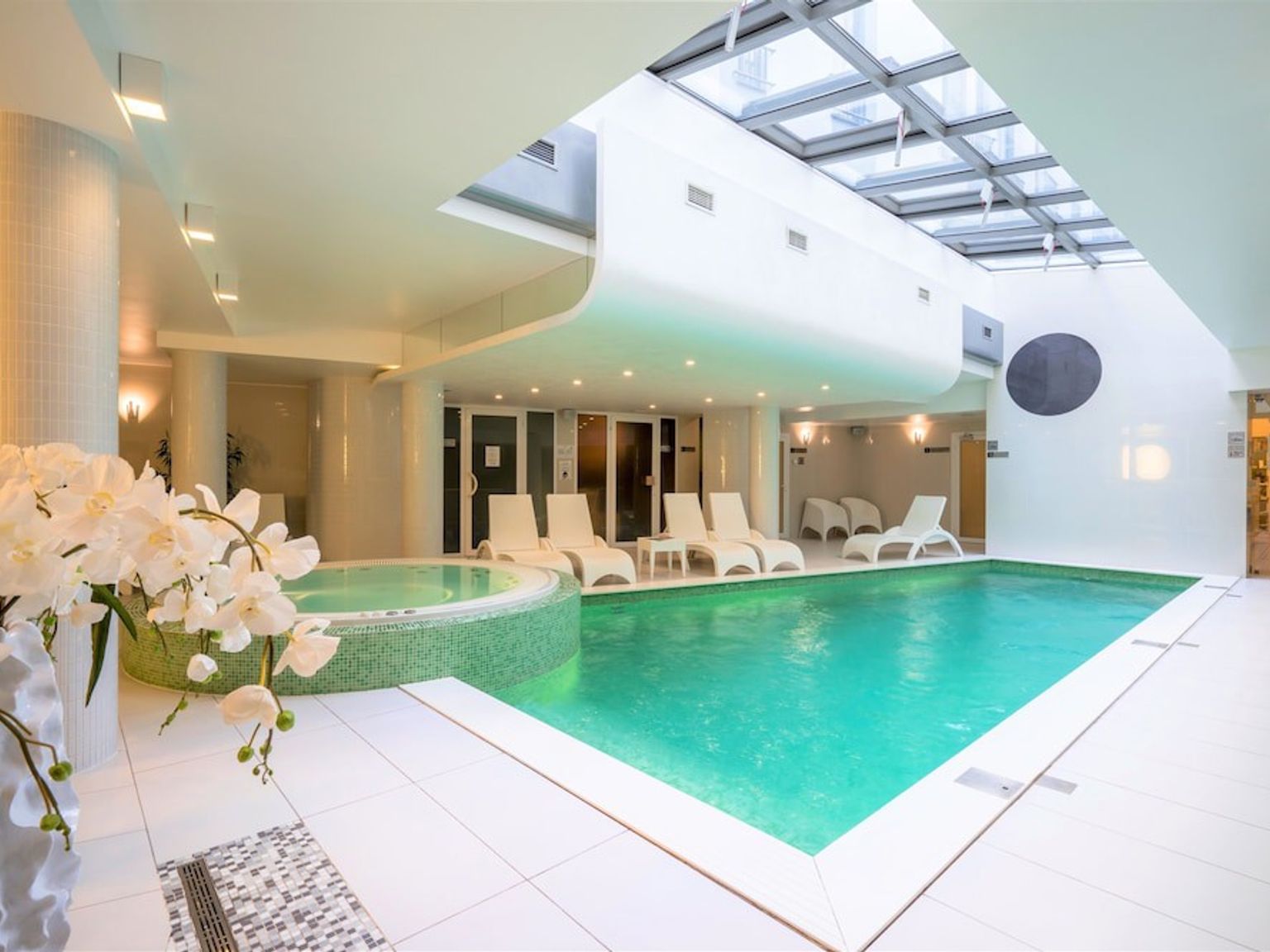 en stor inomhus simbassäng med stolar och blommor i ett spa