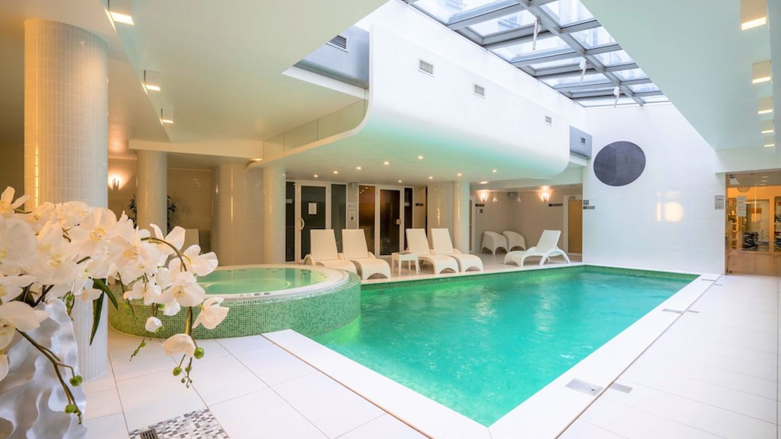 en stor inomhus simbassäng med stolar och blommor i ett spa
