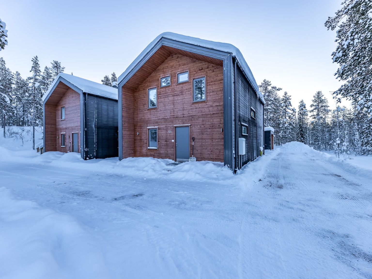 ett stort trähus är omgivet av snö och träd.