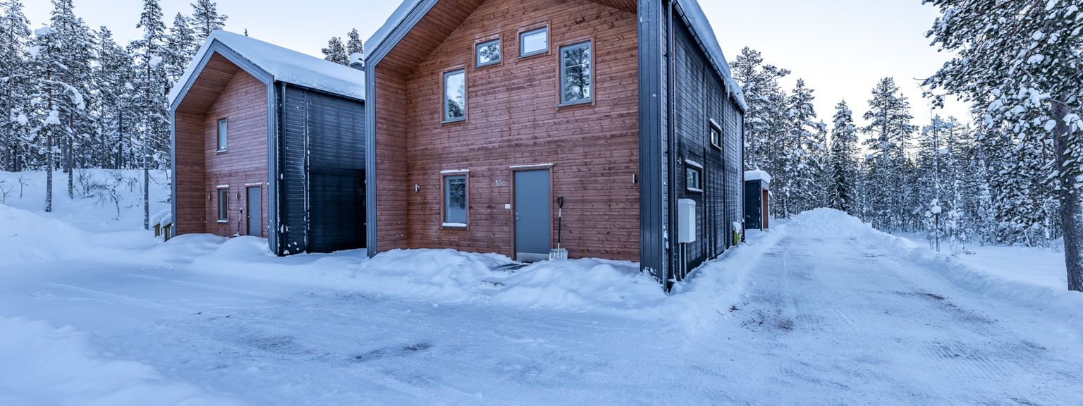 ett stort trähus är omgivet av snö och träd.