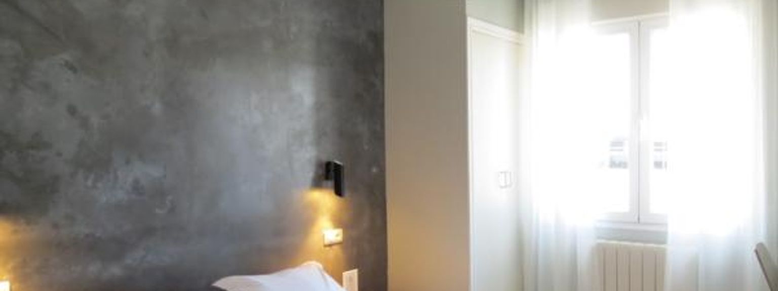 ett sovrum med en king size-sÀng, ett fönster och en grÄ vÀgg
