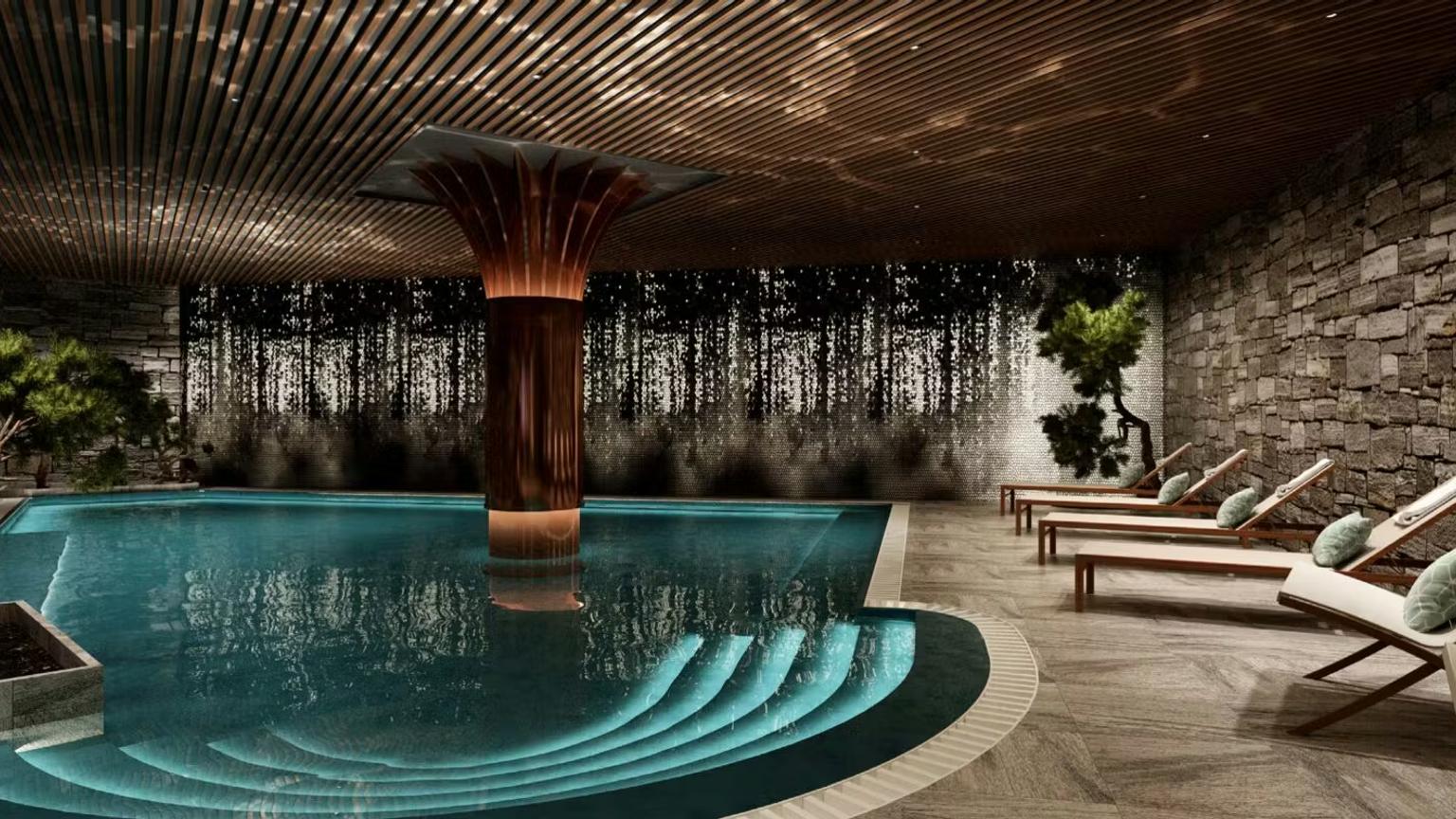 Moderne indendørs swimmingpool med en central kobbersøjle, oplyste trin, stenvægge, et skovmaleri og liggestole.