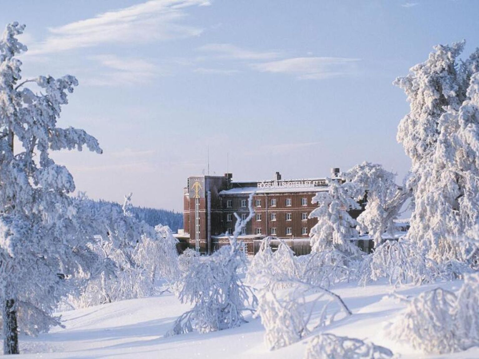 en stor bygning er omgivet af sneklædte træer