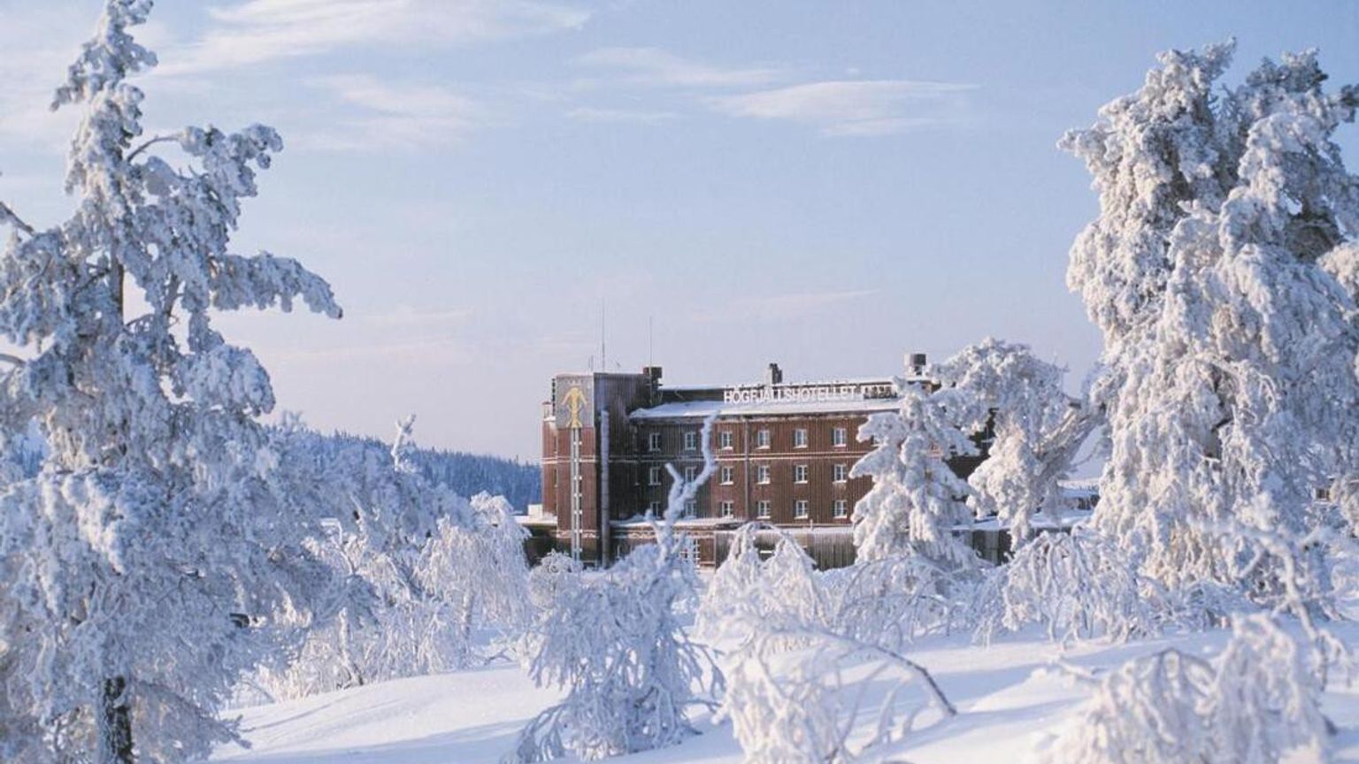 en stor bygning er omgivet af sneklædte træer