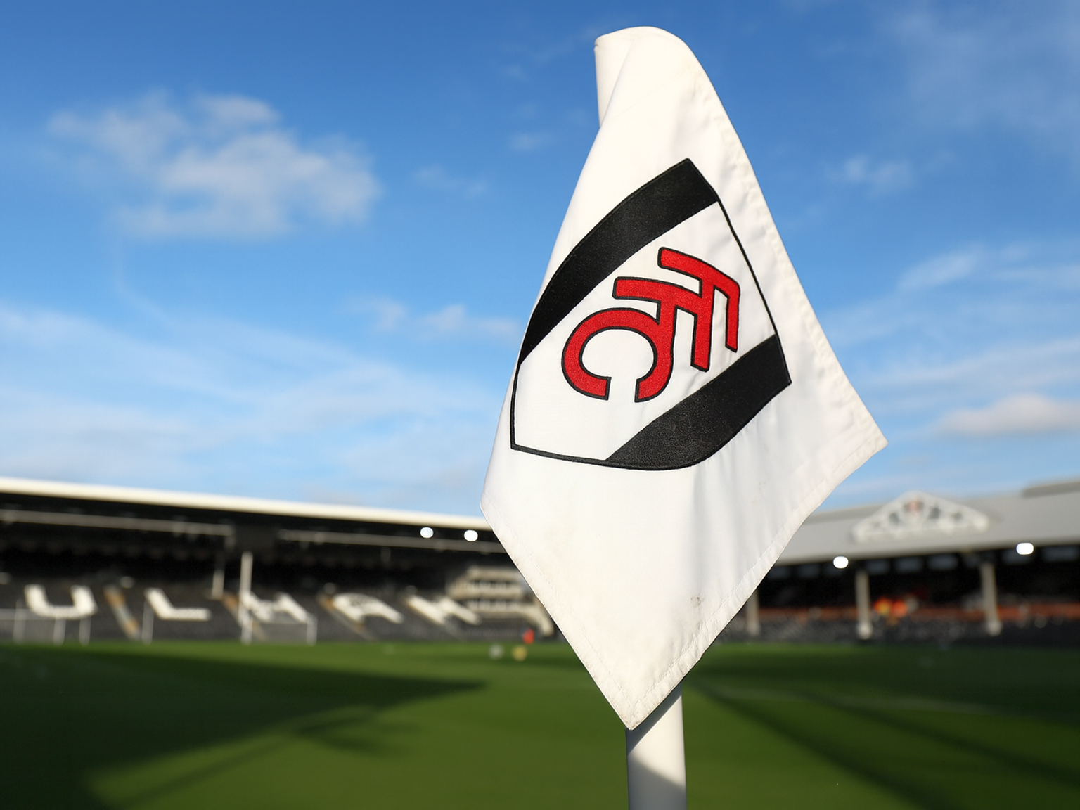 Een hoekvlag met het embleem van Fulham FC in een voetbalstadion.