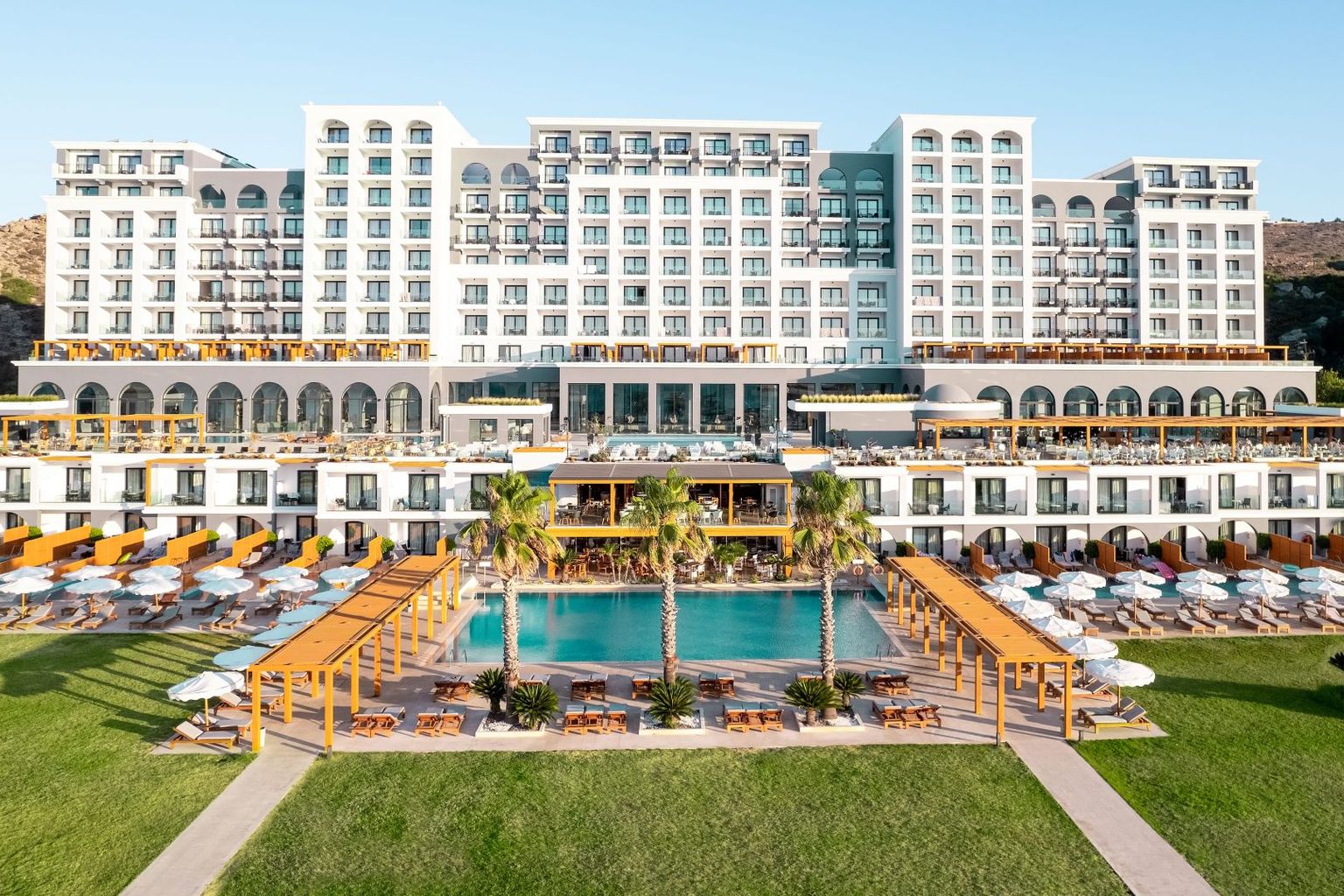Et stort, fleretasjes feriested med flere svømmebassenger, grønne plener og rekker med solsenger. Mitsis Selection Alila