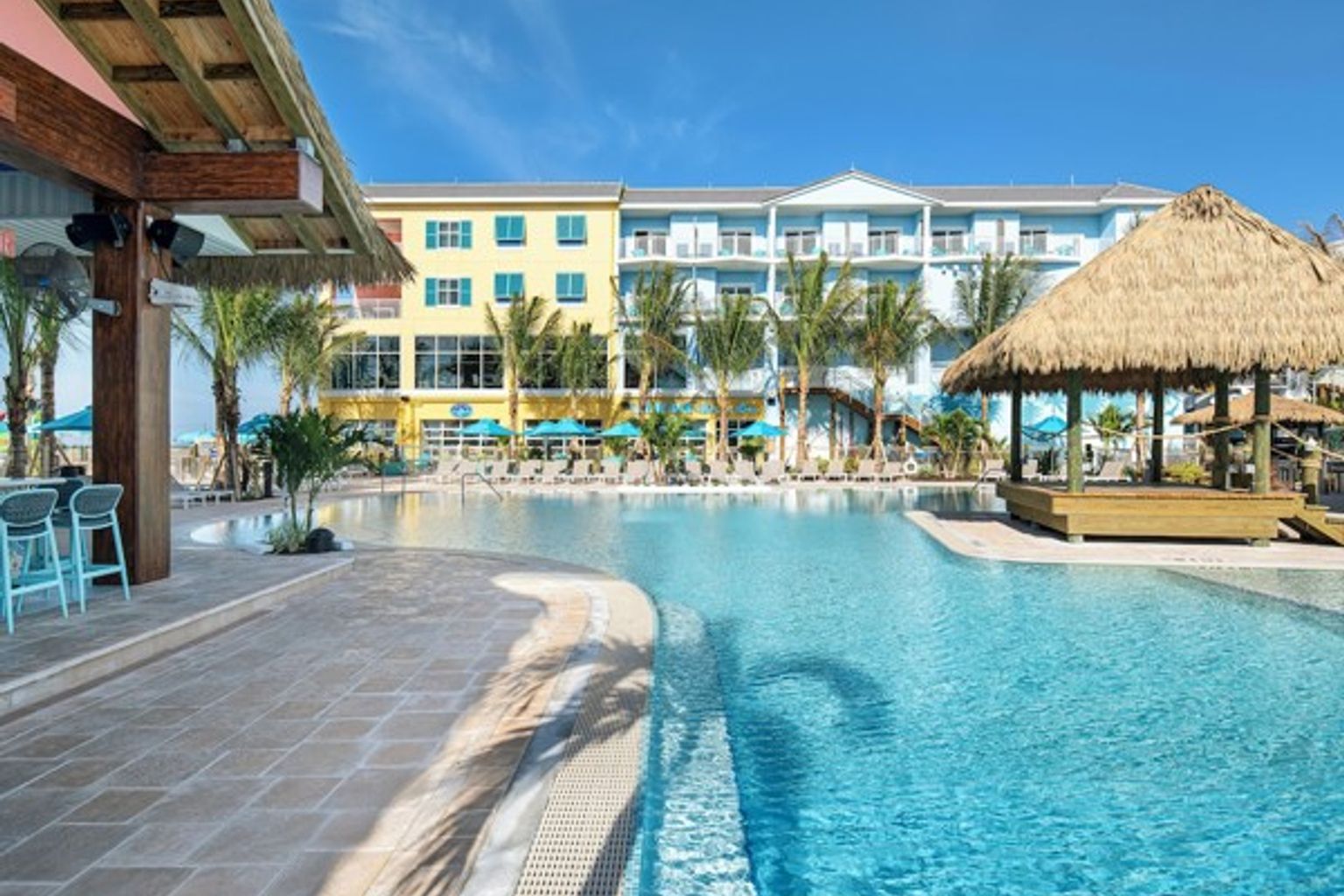 et stort svømmebasseng med en stråtekt hytte foran et hotell