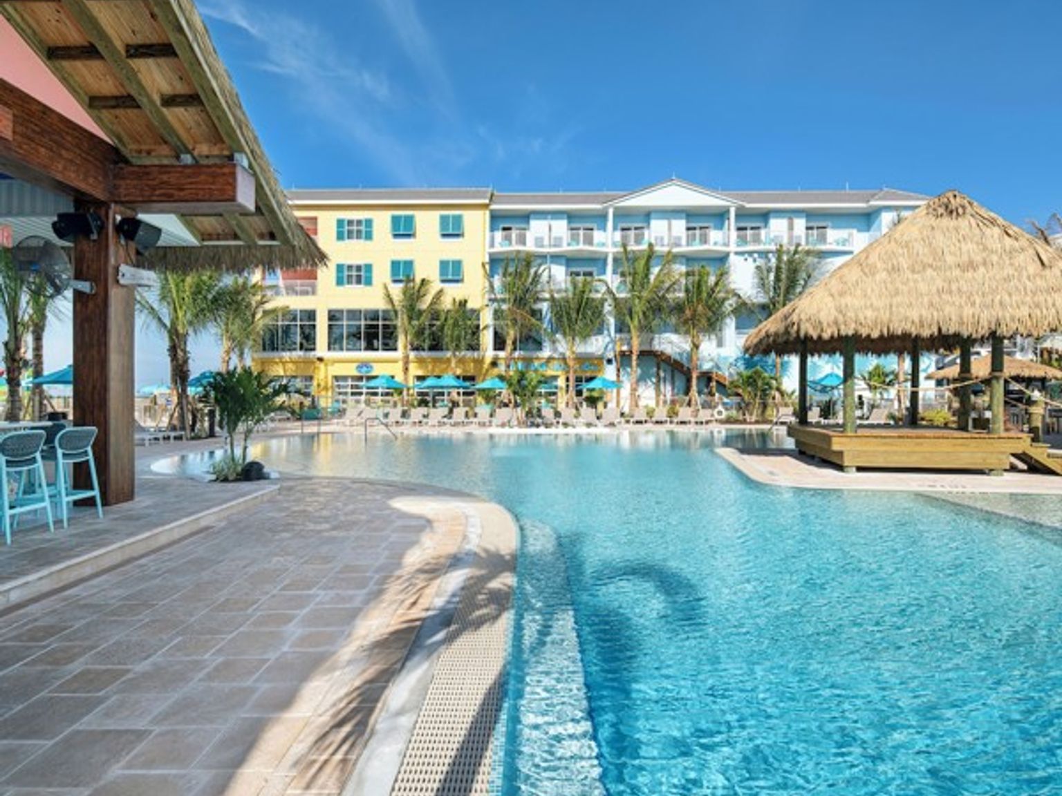 et stort svømmebasseng med en stråtekt hytte foran et hotell