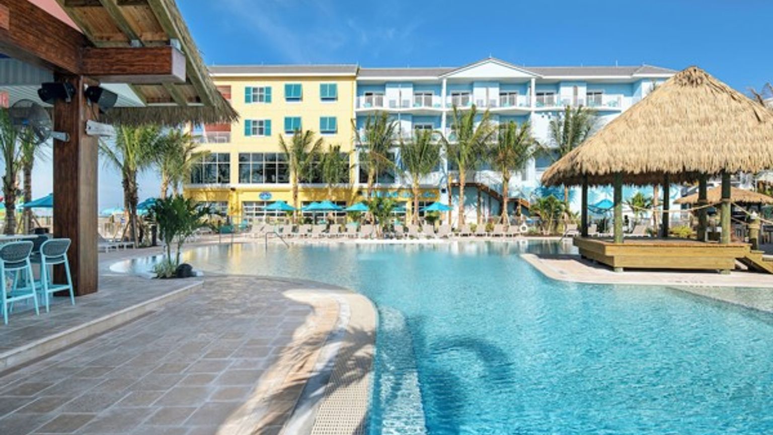 et stort svømmebasseng med en stråtekt hytte foran et hotell