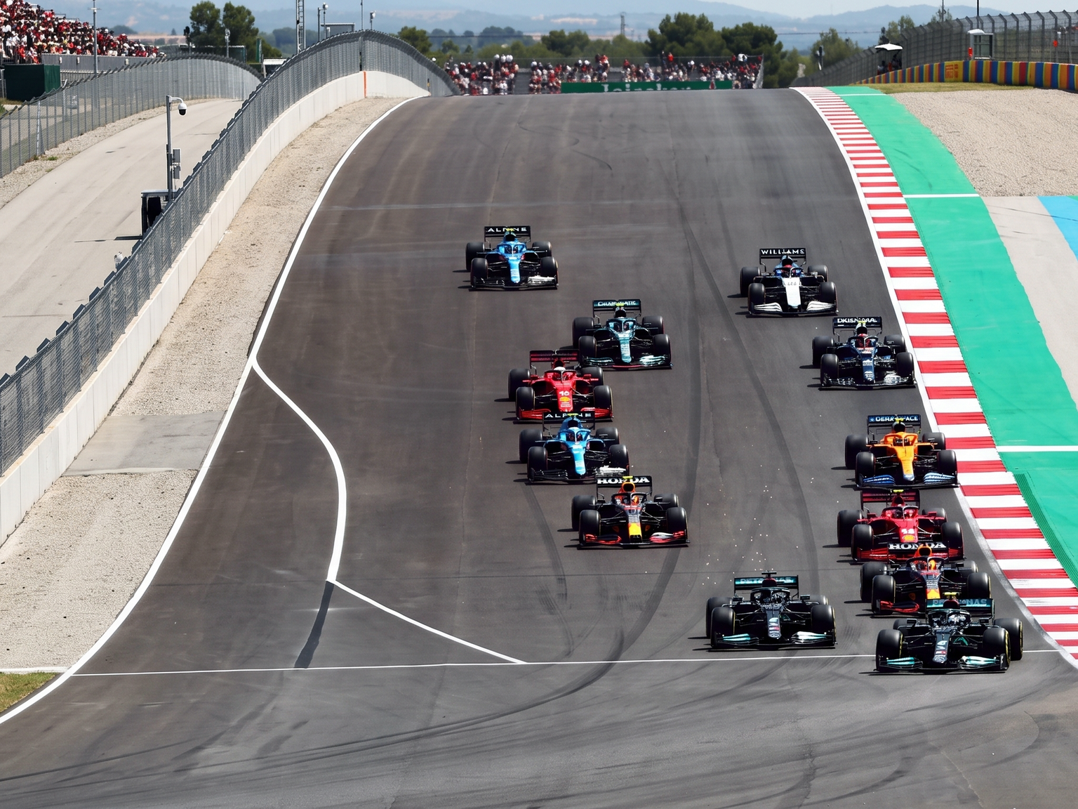 Meerdere Formule 1-auto's racen bergopwaarts op een circuit.