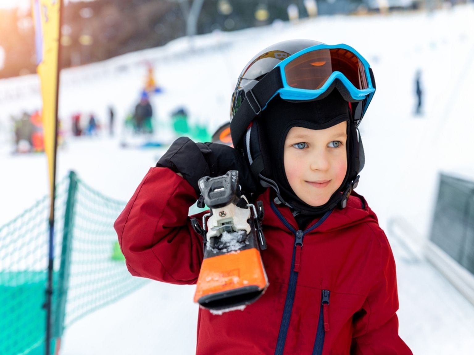 en ung pojke med hjälm och goggles håller i en snowboard
