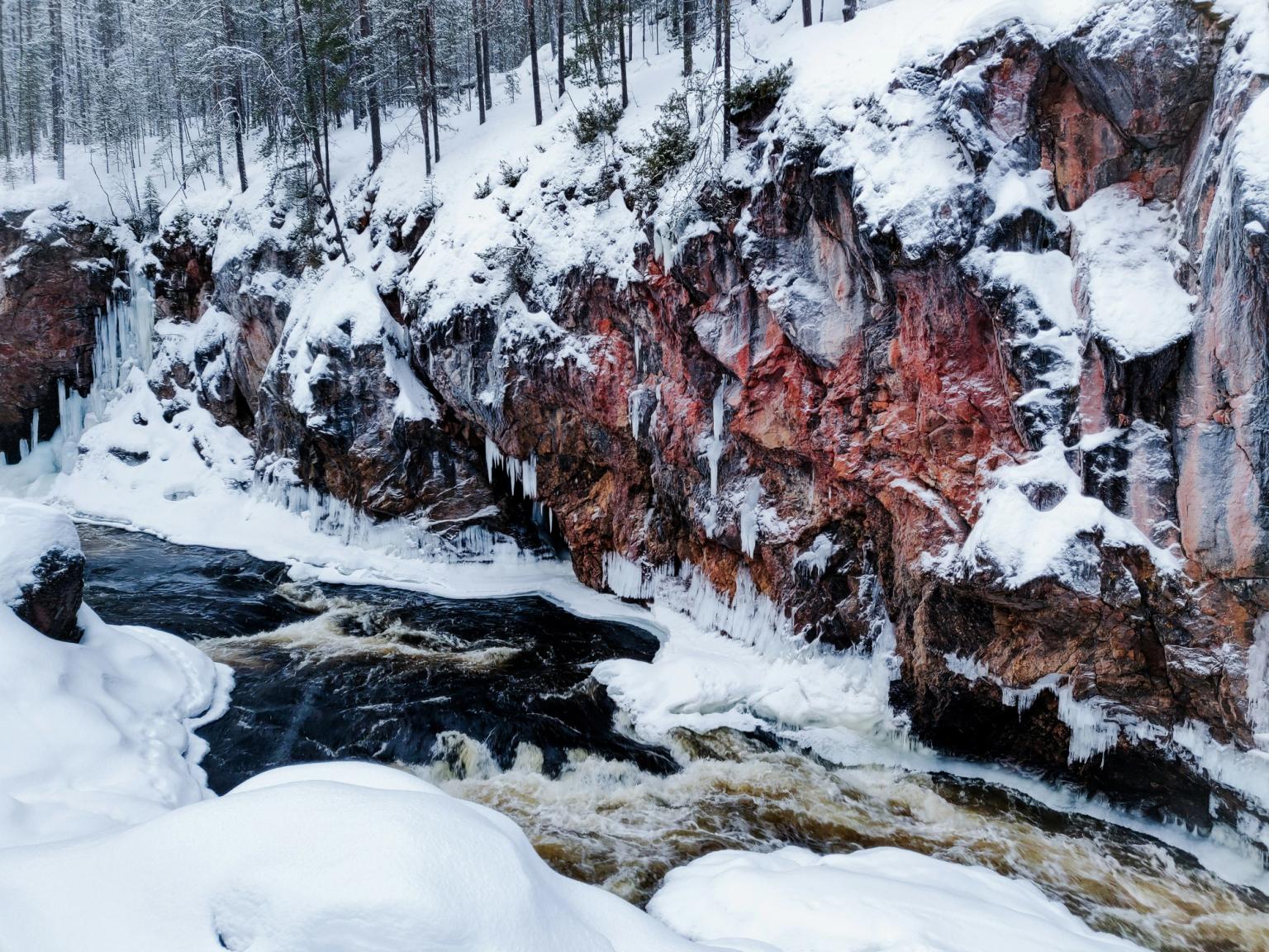 una vista aérea de un río rodeado de rocas y árboles cubiertos de nieve