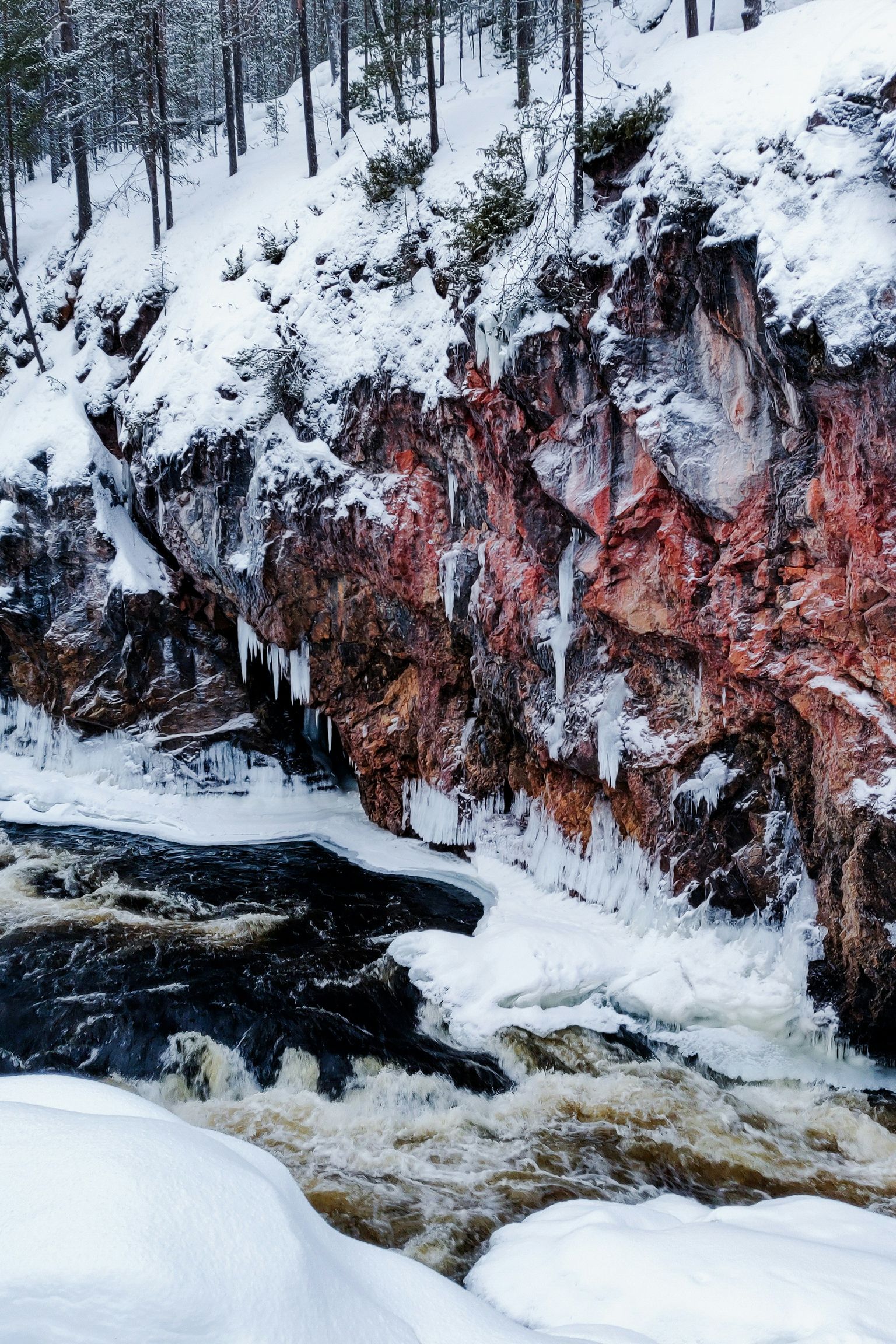 una vista aérea de un río rodeado de rocas y árboles cubiertos de nieve