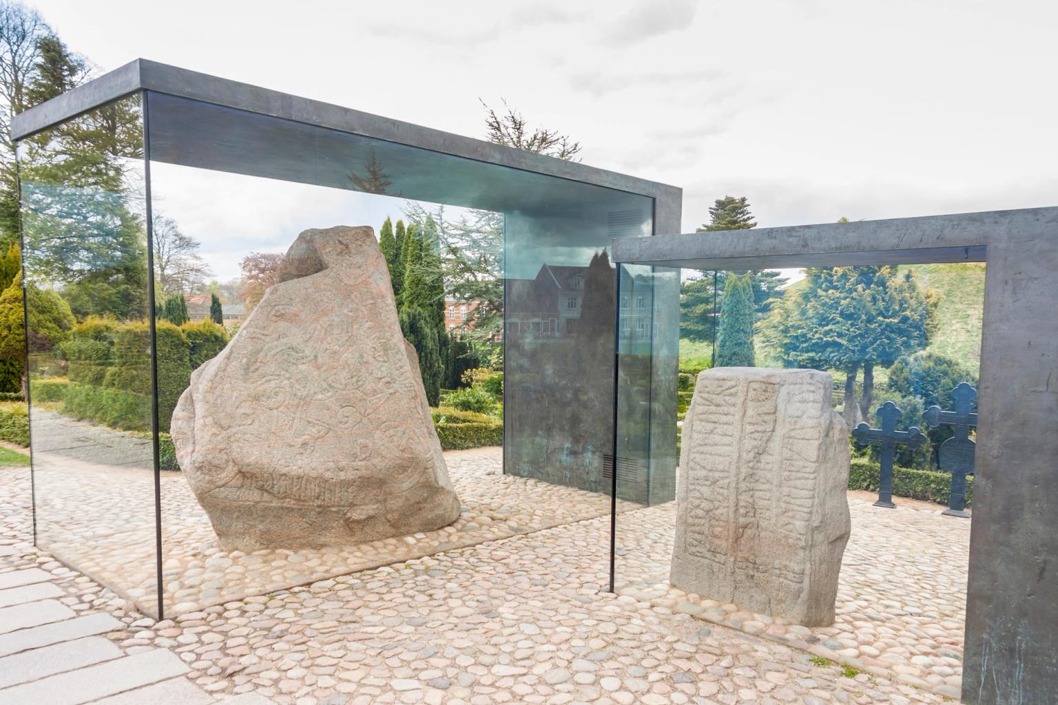 en stor sten sitter under ett glasvisningsfodral i en park