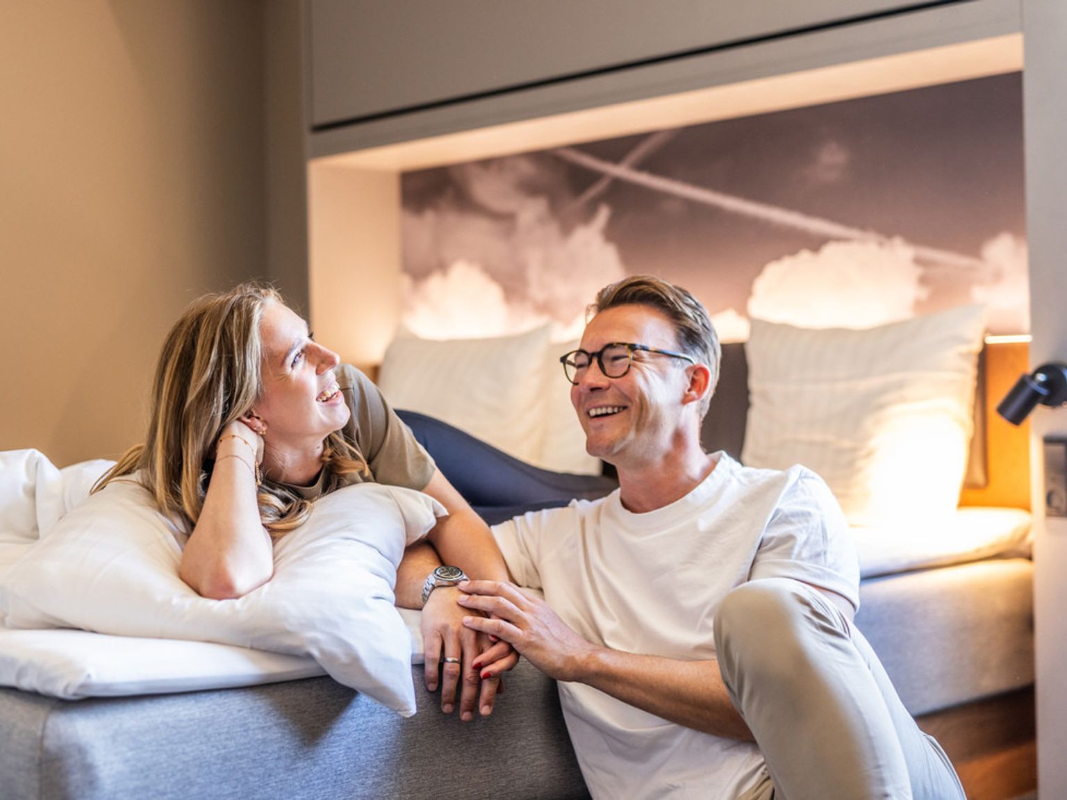 Ett lyckligt par som ler och kopplar av i ett modernt sovrum. Billund Airport hotell