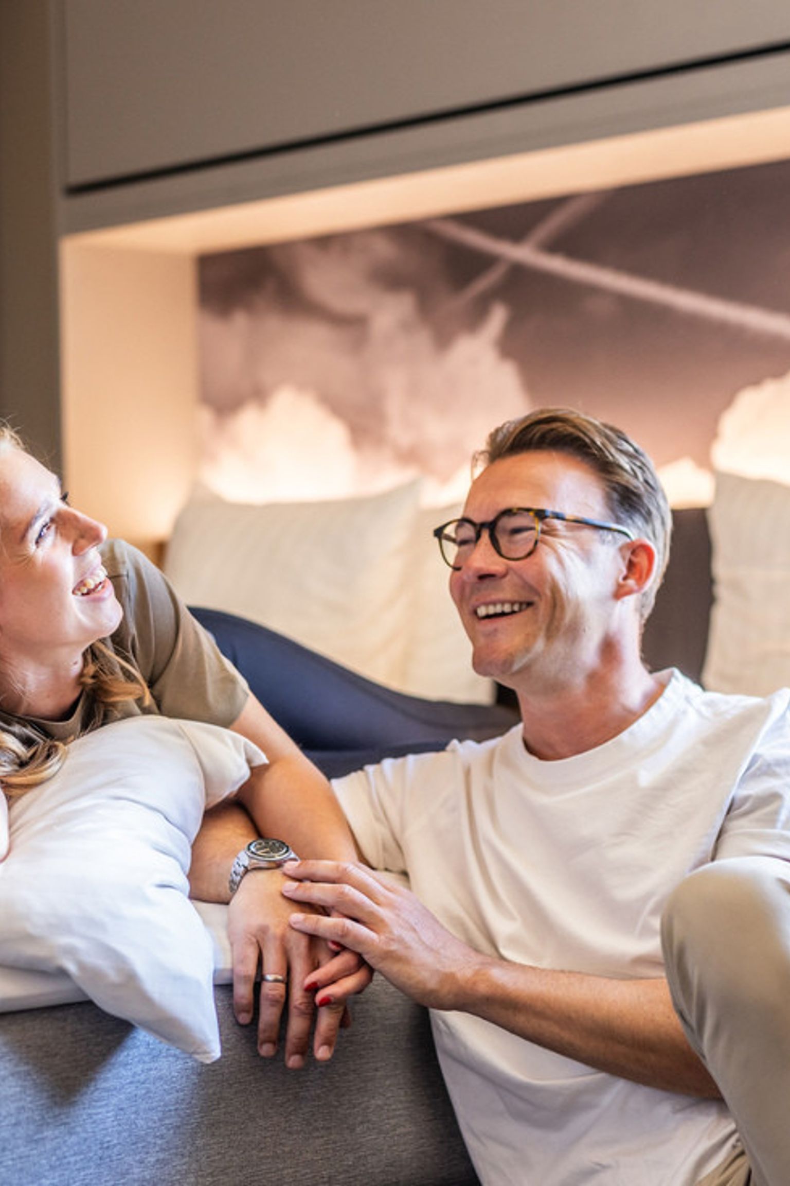 Ett lyckligt par som ler och kopplar av i ett modernt sovrum. Billund Airport hotell