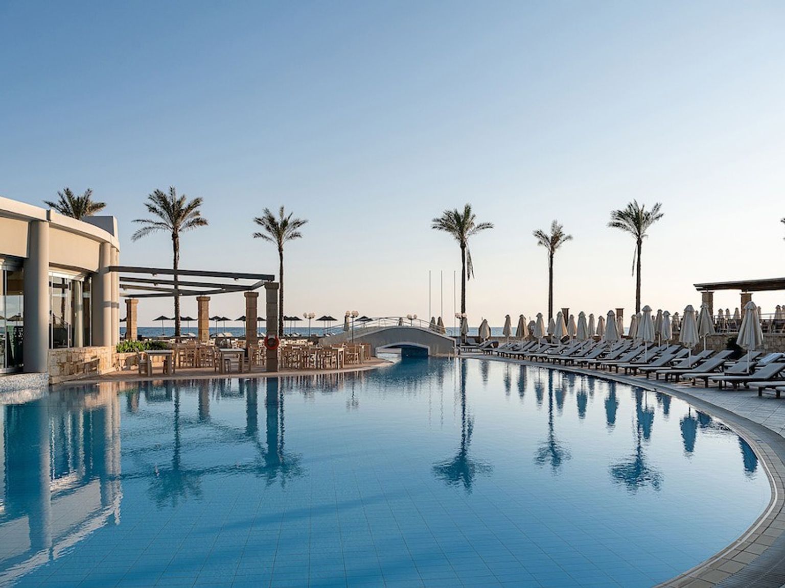 en stor swimmingpool omgiven av palmer och stolar på en resort