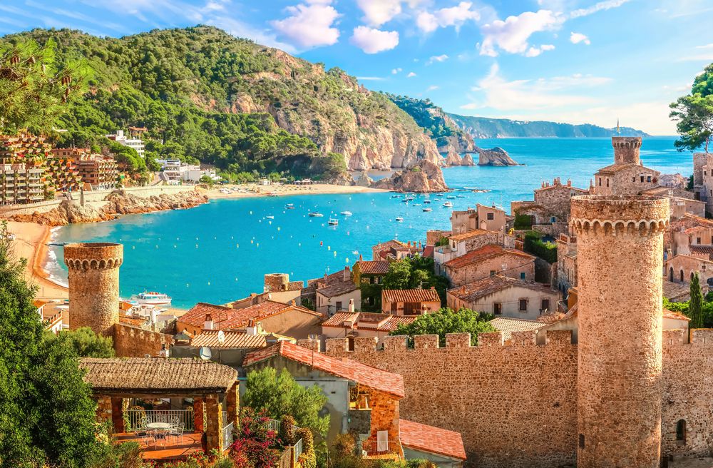 Historisk kystby med stentårne, rødtagsbygninger, en sandstrand og en turkis bugt med både. Tossa de Mar, Spanien