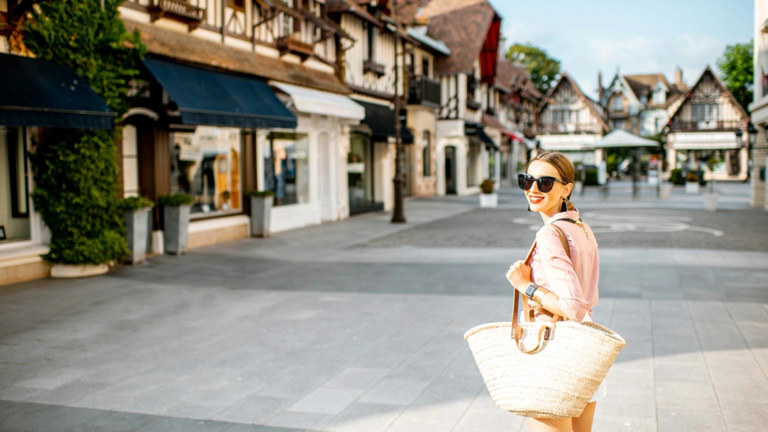kobieta idzie ulicą trzymając torbę ze słomy