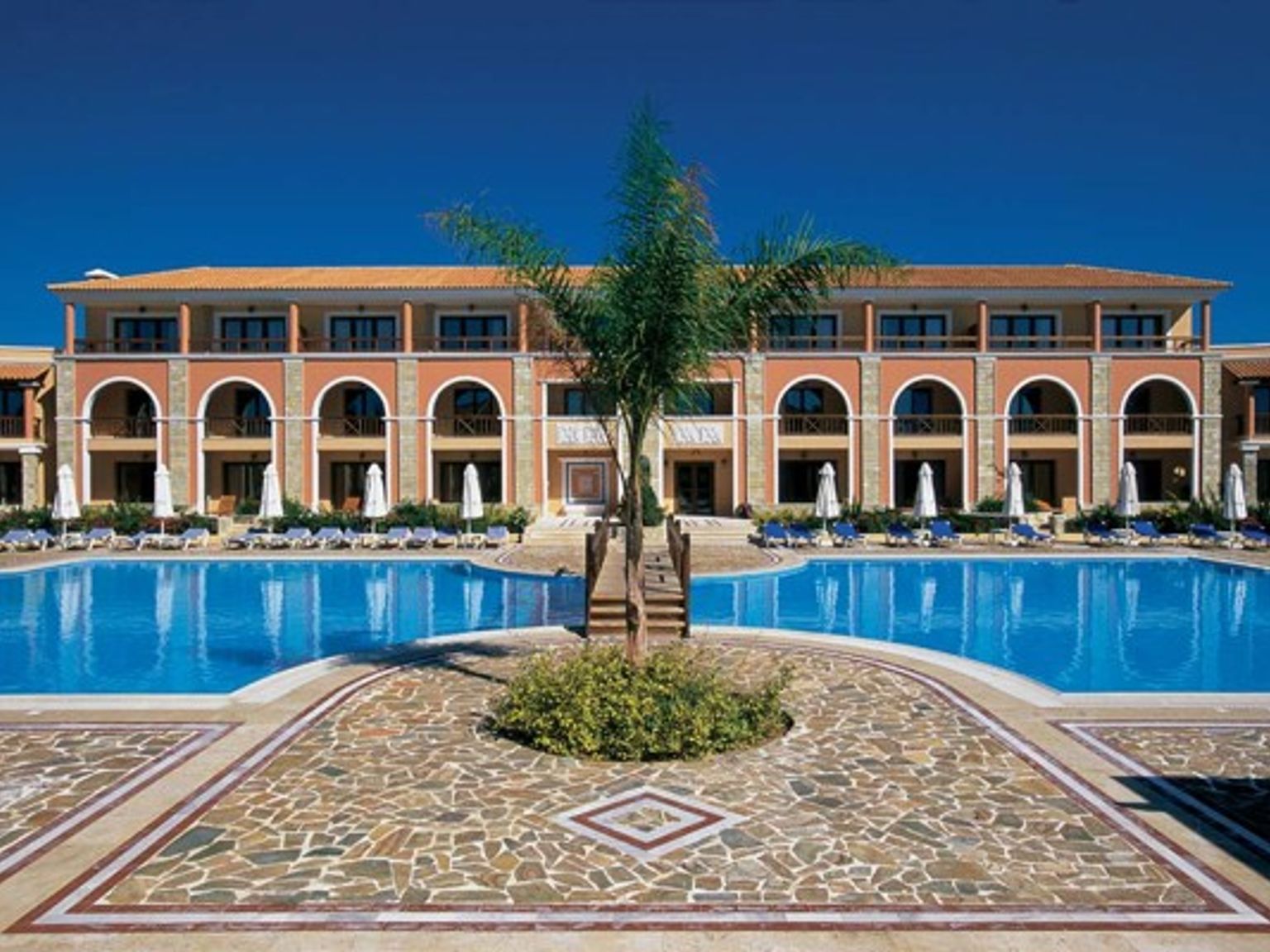 ett stort hotell med en stor simbassäng framför det