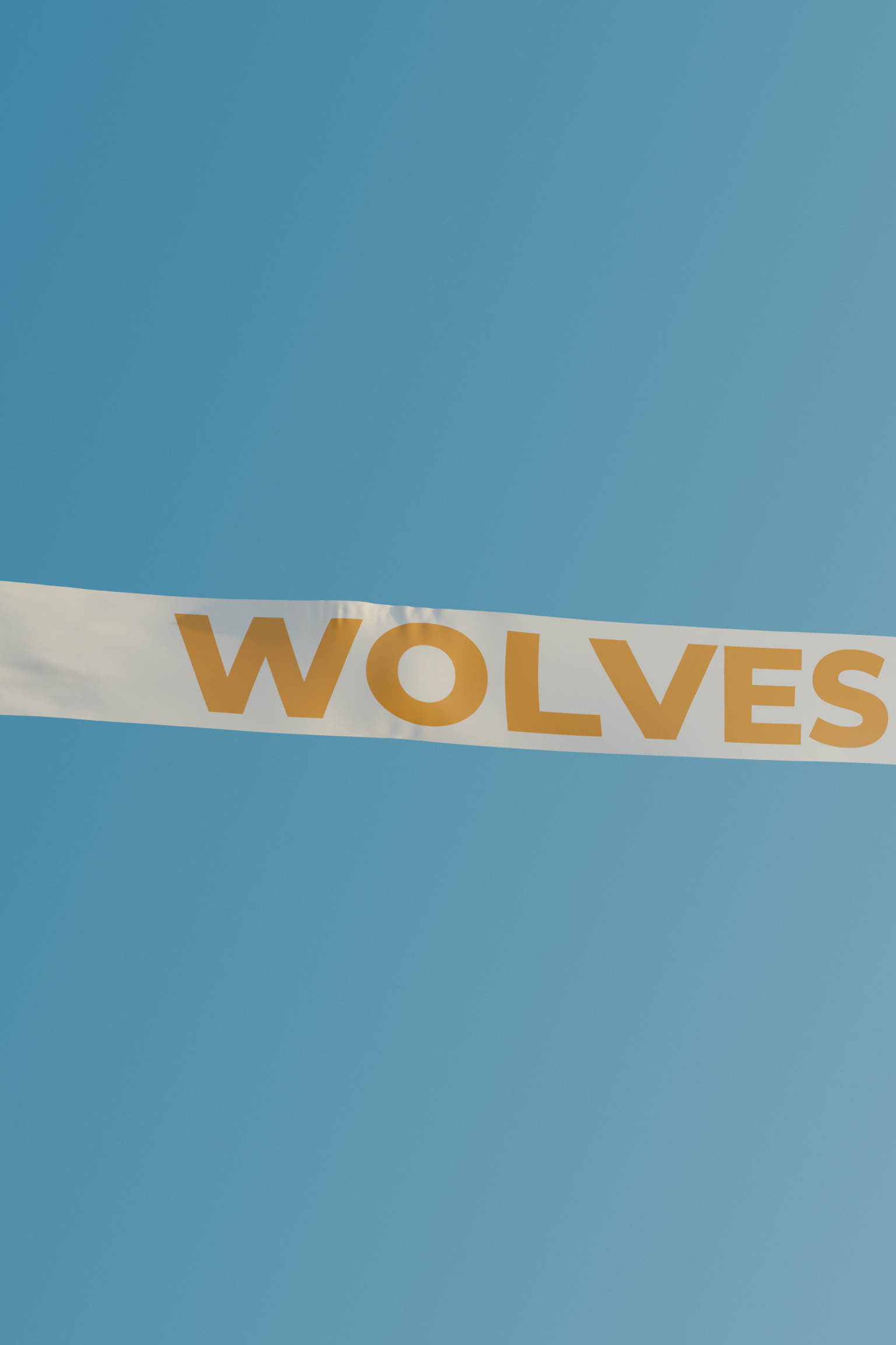 Un avion rouge tire une bannière avec l'inscription "WOLVES" à travers un ciel bleu.