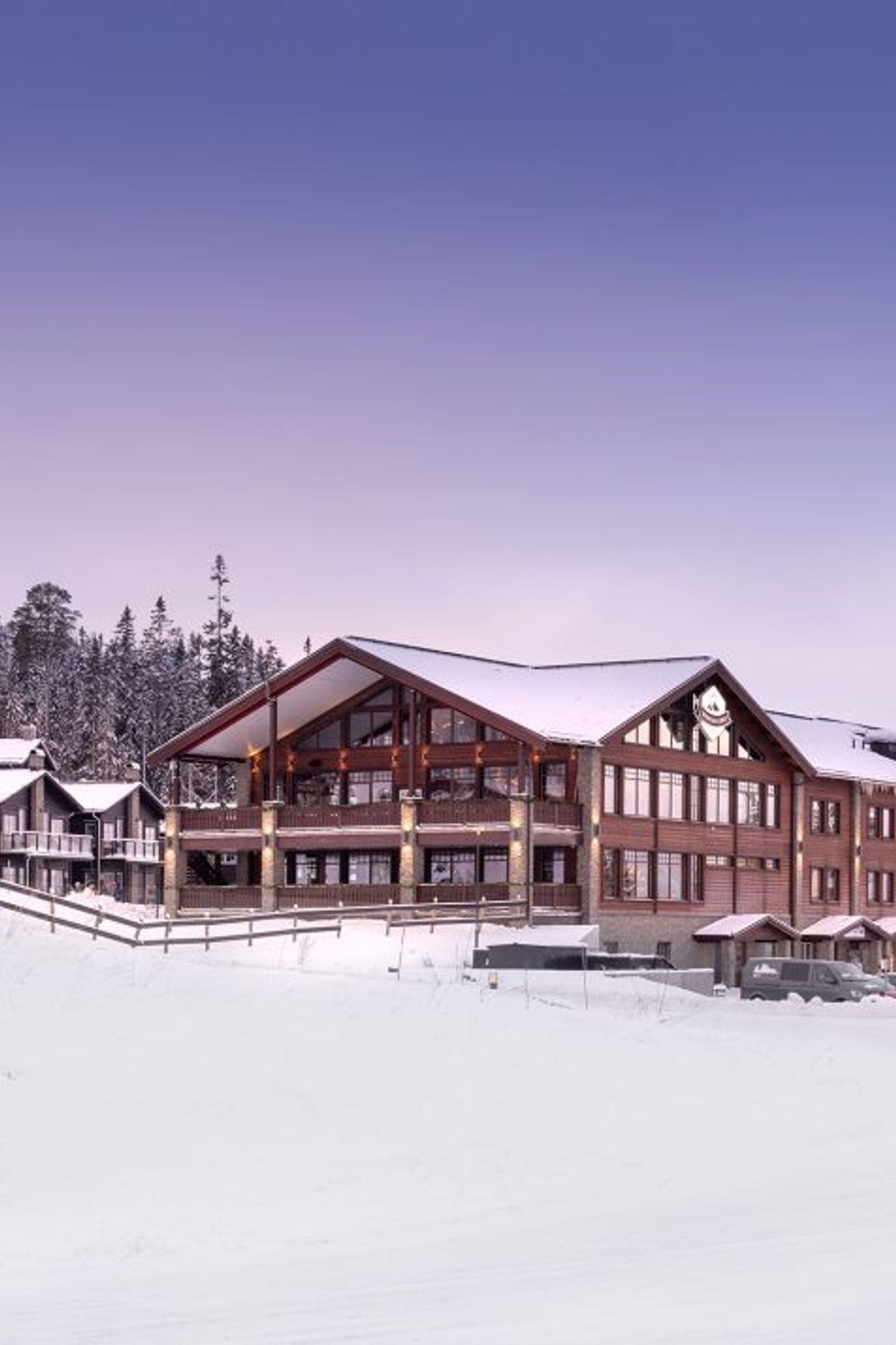 en snømann står foran en stor bygning dekket av snø