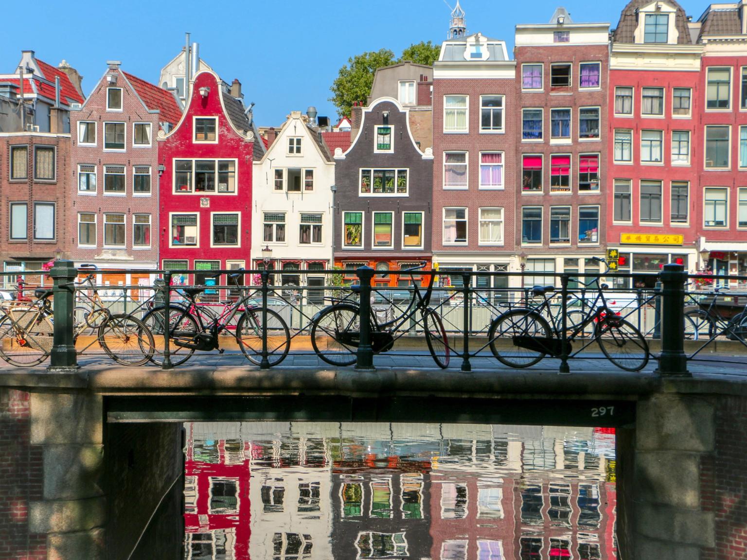 un groupe de vélos est garé sur un pont au-dessus d'un canal à Amsterdam.