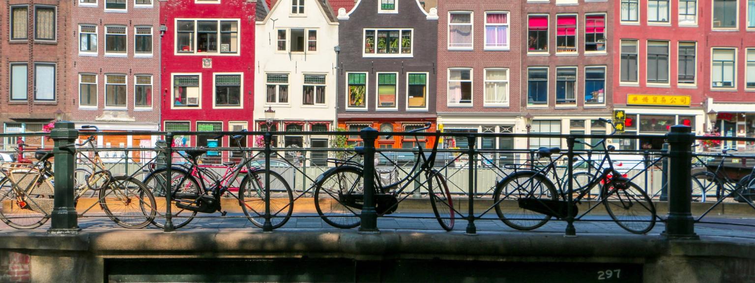 en grupp cyklar är parkerade på en bro över en kanal i Amsterdam.