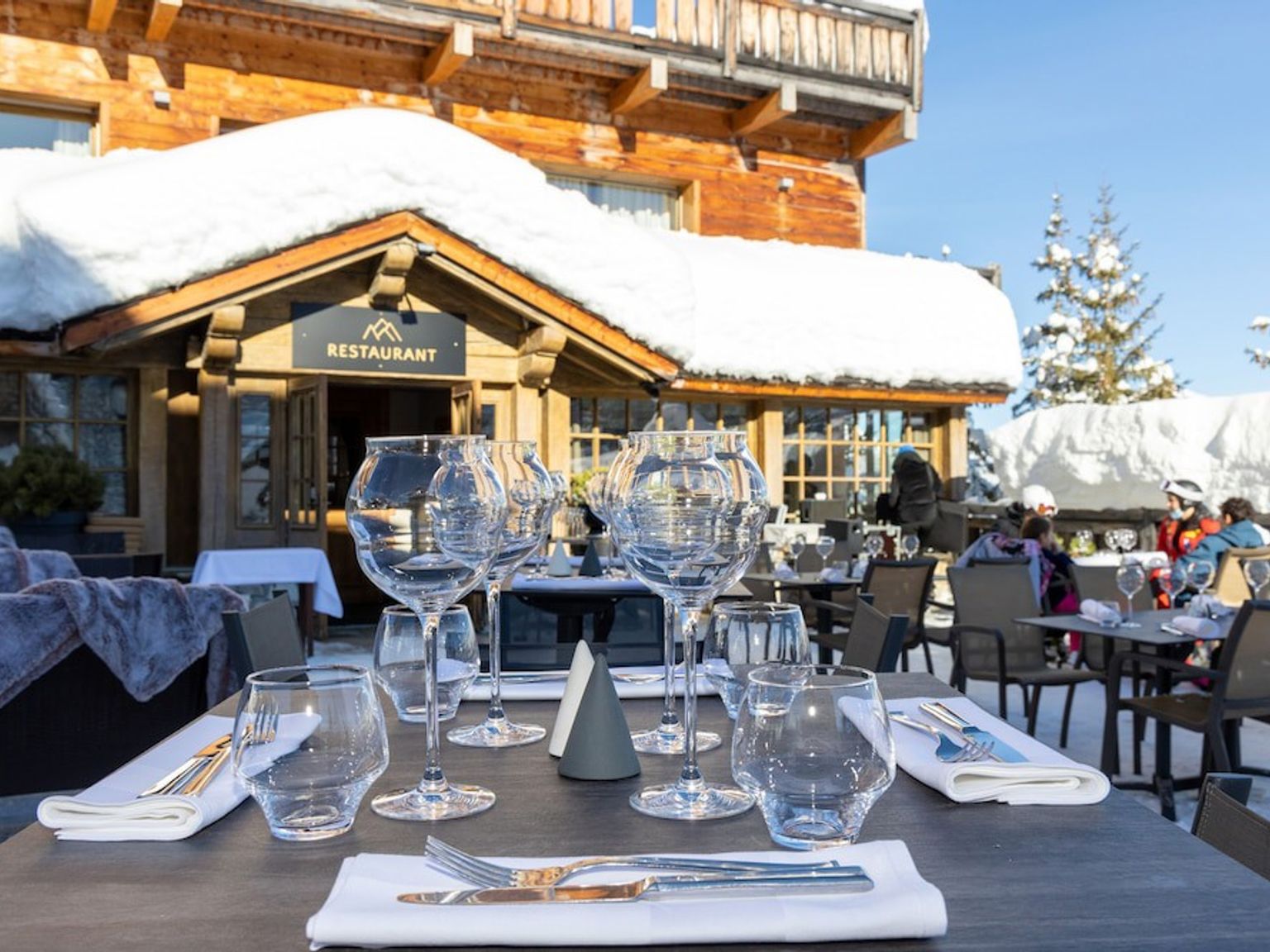 et bord dekket for et måltid foran en restaurant dekket av snø.