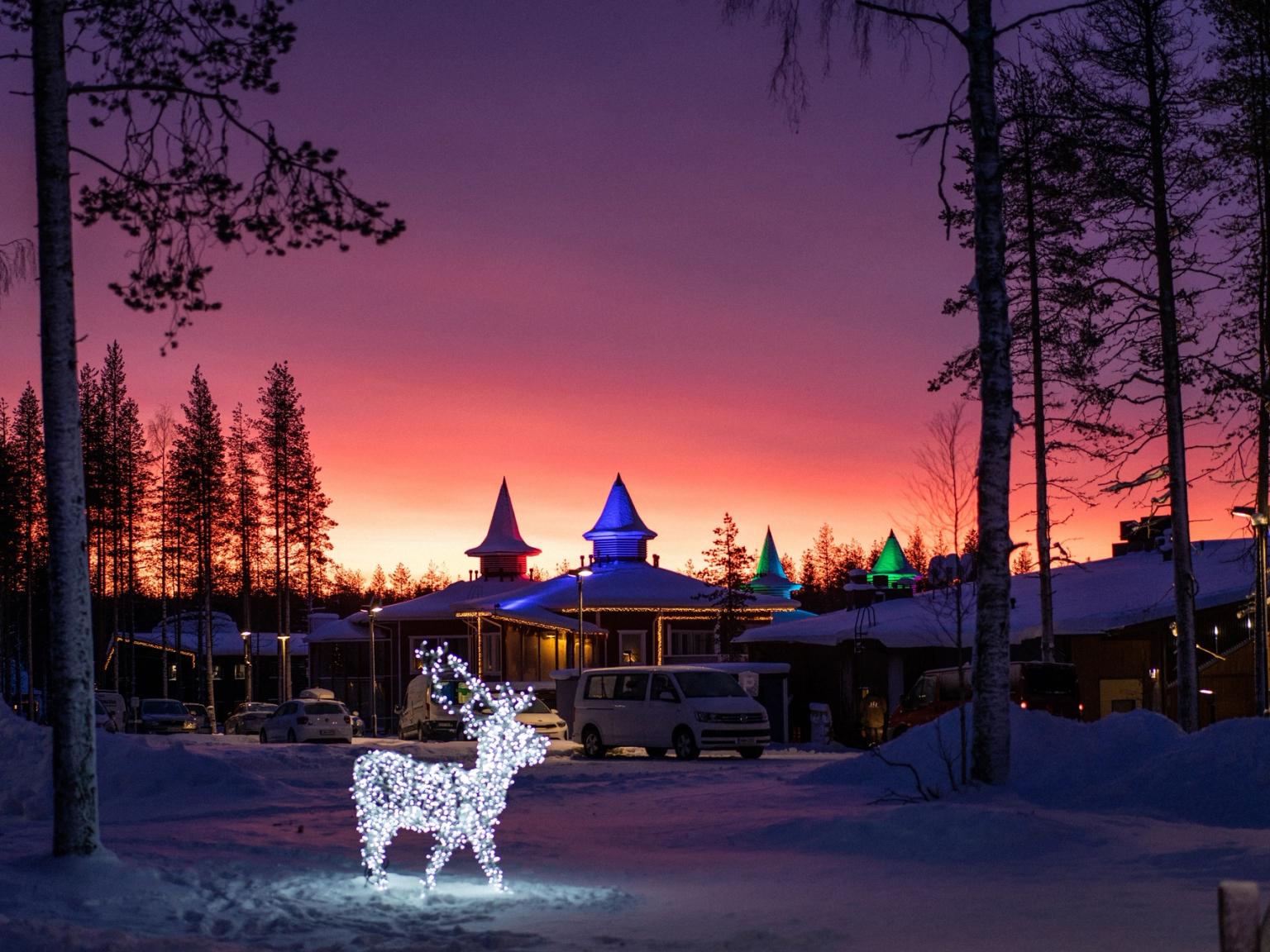ein Rentier aus Weihnachtslichtern leuchtet im Schnee vor einem Gebäude