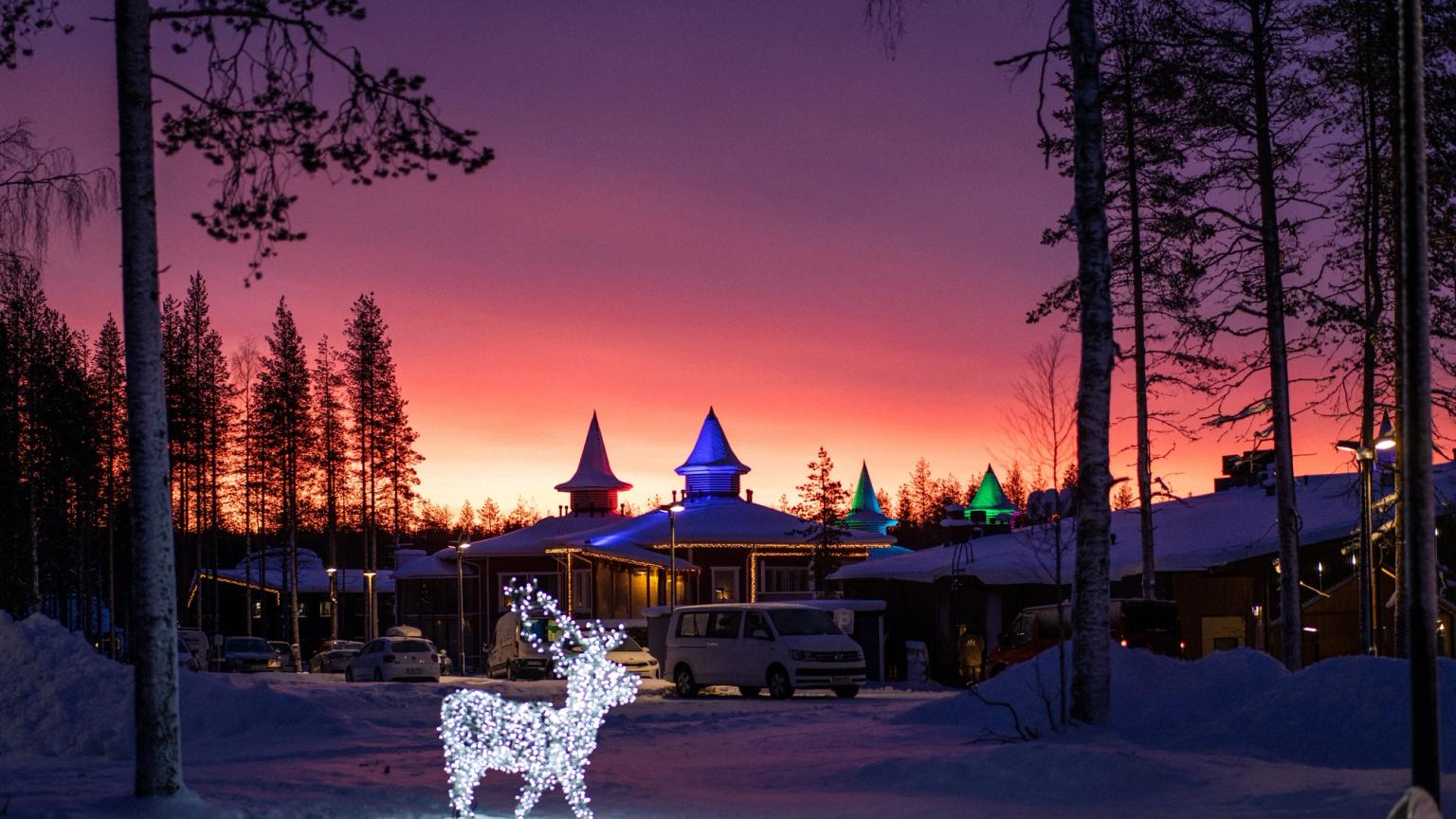 ein Rentier aus Weihnachtslichtern leuchtet im Schnee vor einem Gebäude