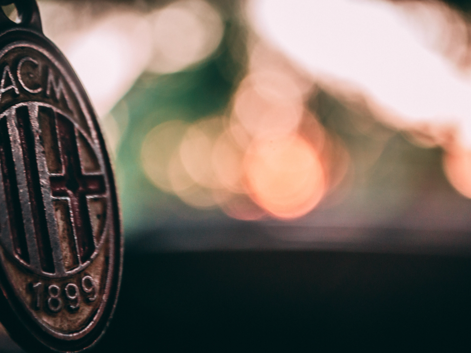 Close-up of a rustic AC Milan logo with a blurred bokeh background.