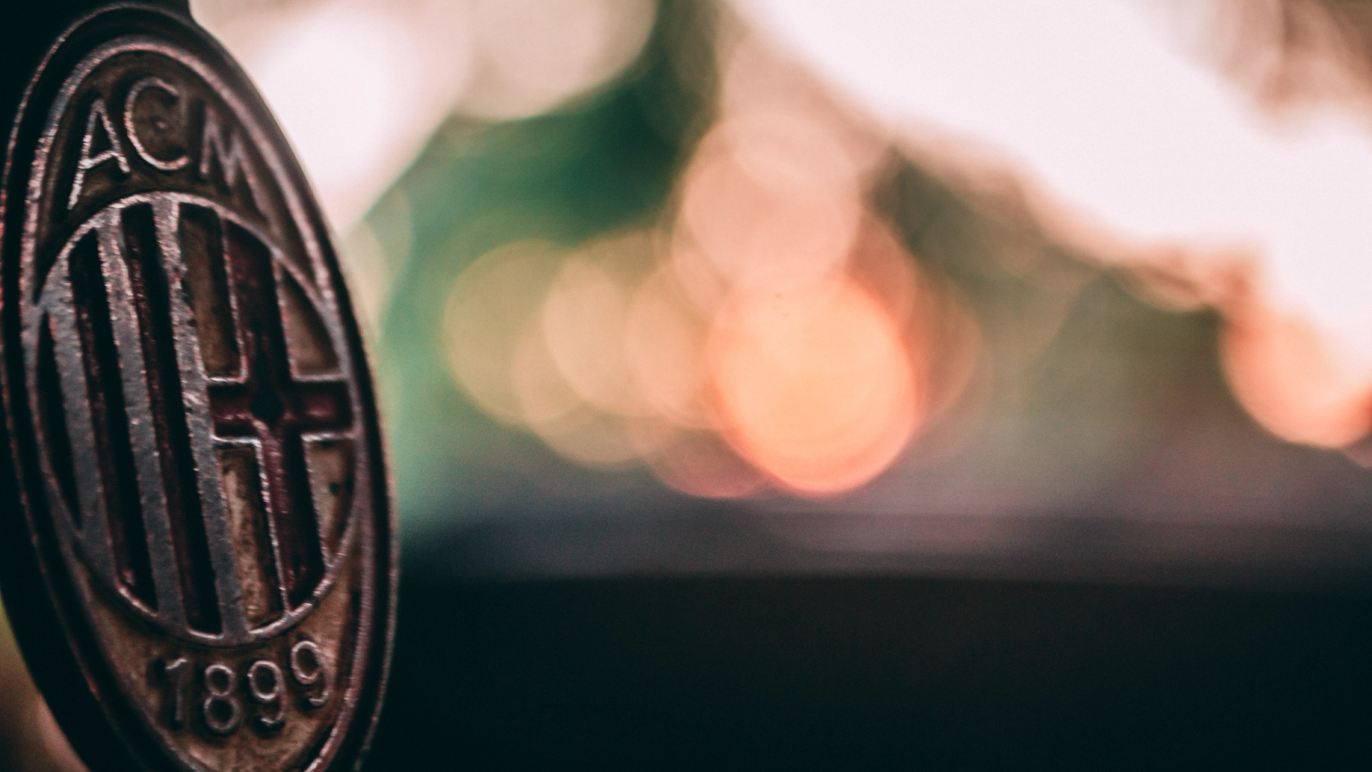Close-up of a rustic AC Milan logo with a blurred bokeh background.