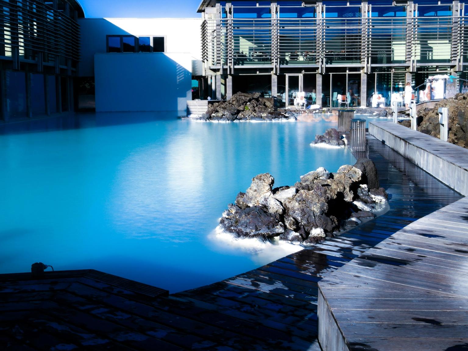 a large swimming pool surrounded by rocks and a building