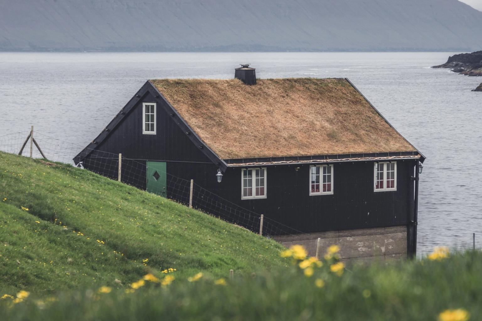 a black house sits on a hill overlooking the ocean