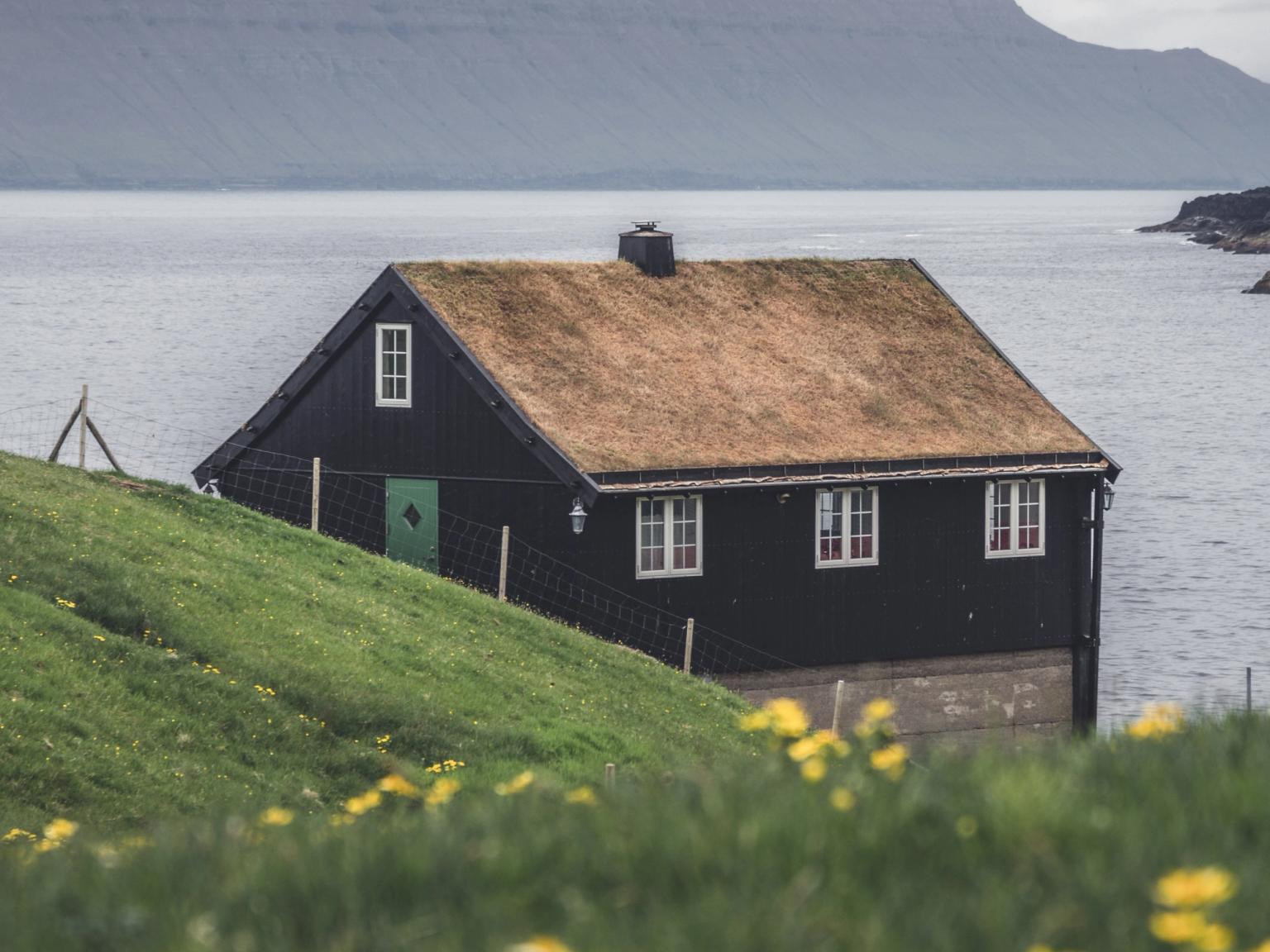 a black house sits on a hill overlooking the ocean