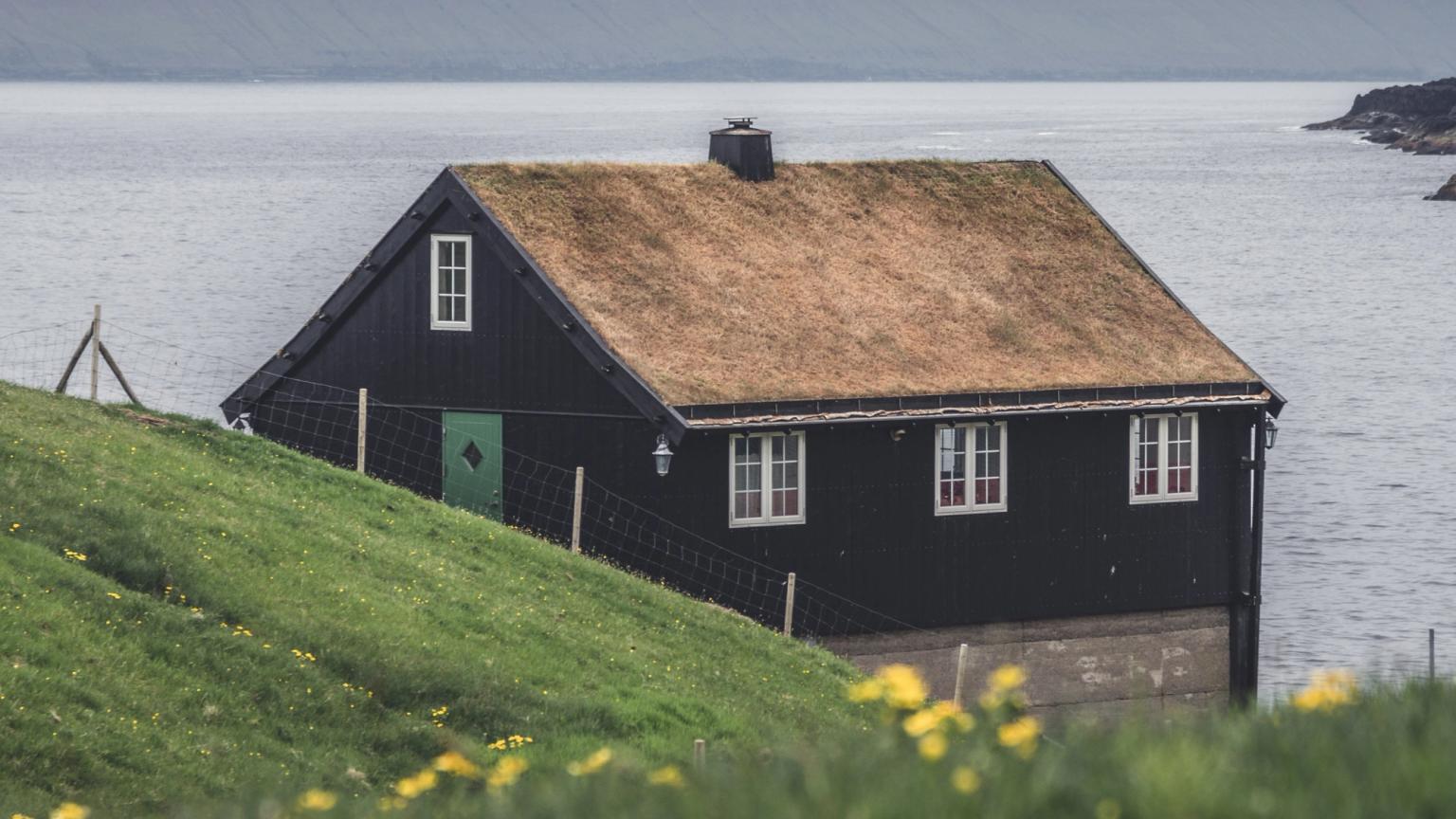a black house sits on a hill overlooking the ocean