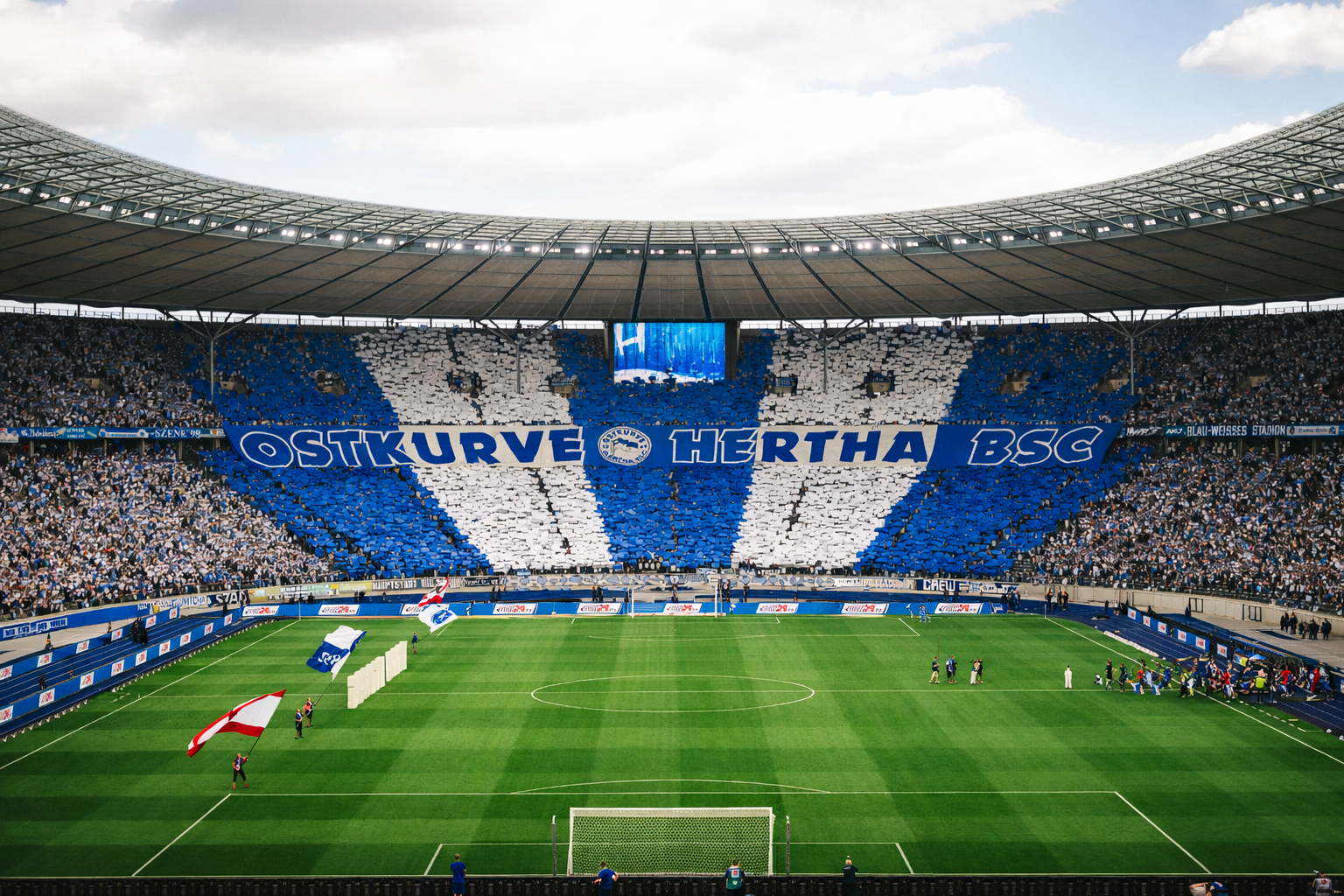 Fans in einem großen Fußballstadion zeigen ein blau-weißes Tifo mit der Aufschrift 'OSTKURVE HERTHA BSC'.