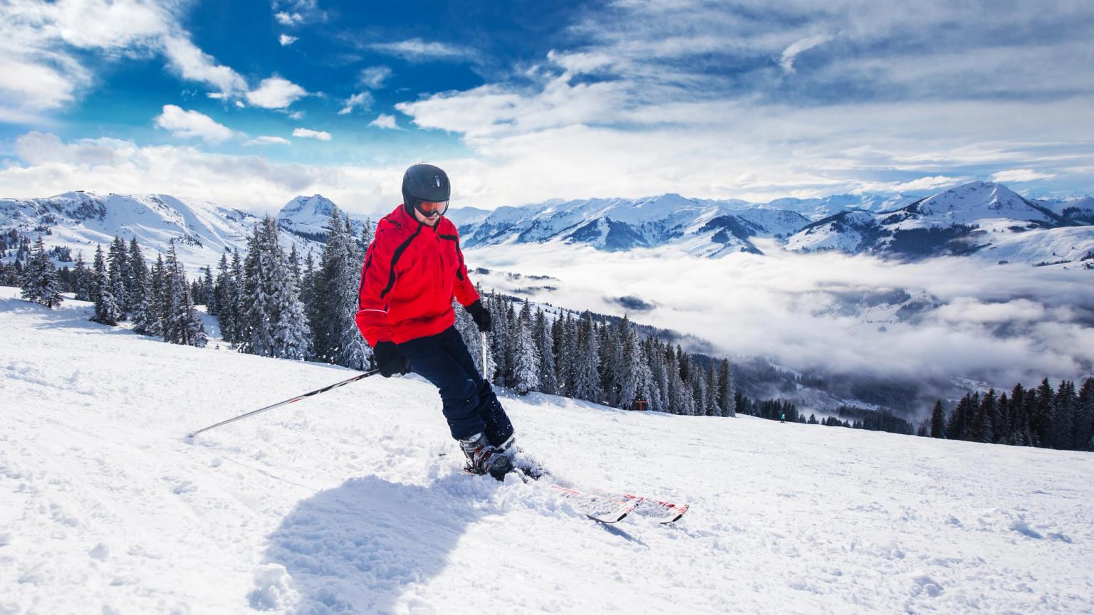 en mand står på ski ned ad et sneklædt bjerg