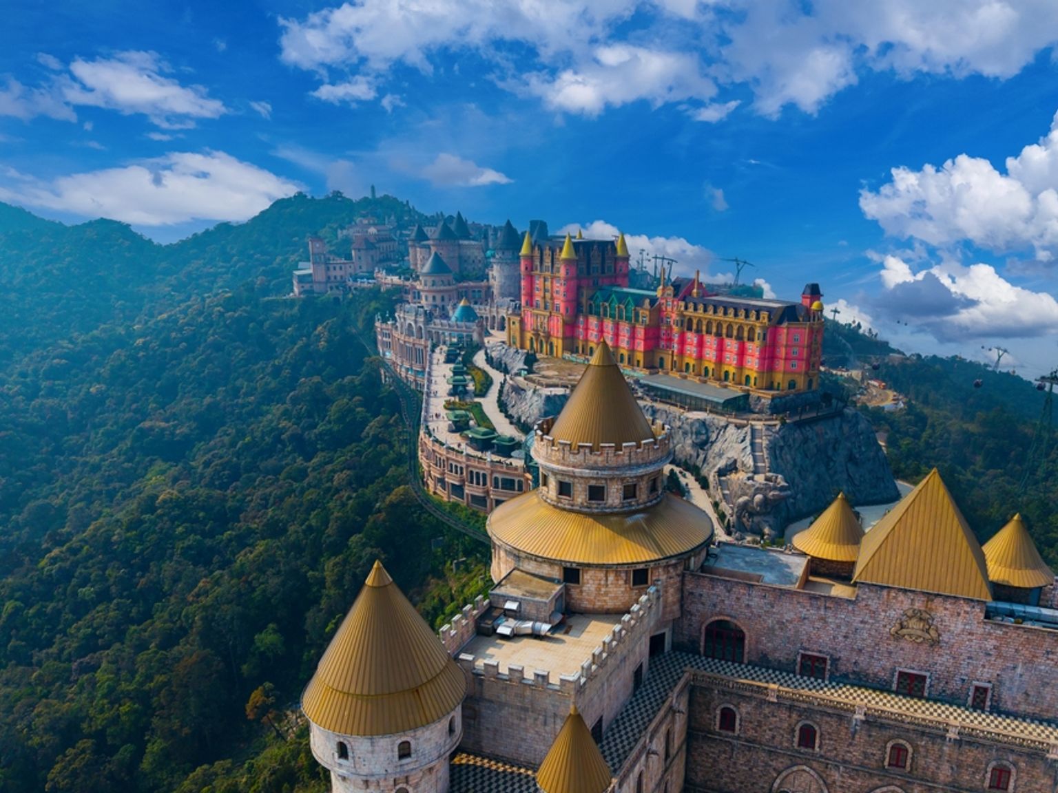 Et levende slotskompleks breder sig over et skovklædt bjerg under en blå himmel. Da Nang - Vietnam