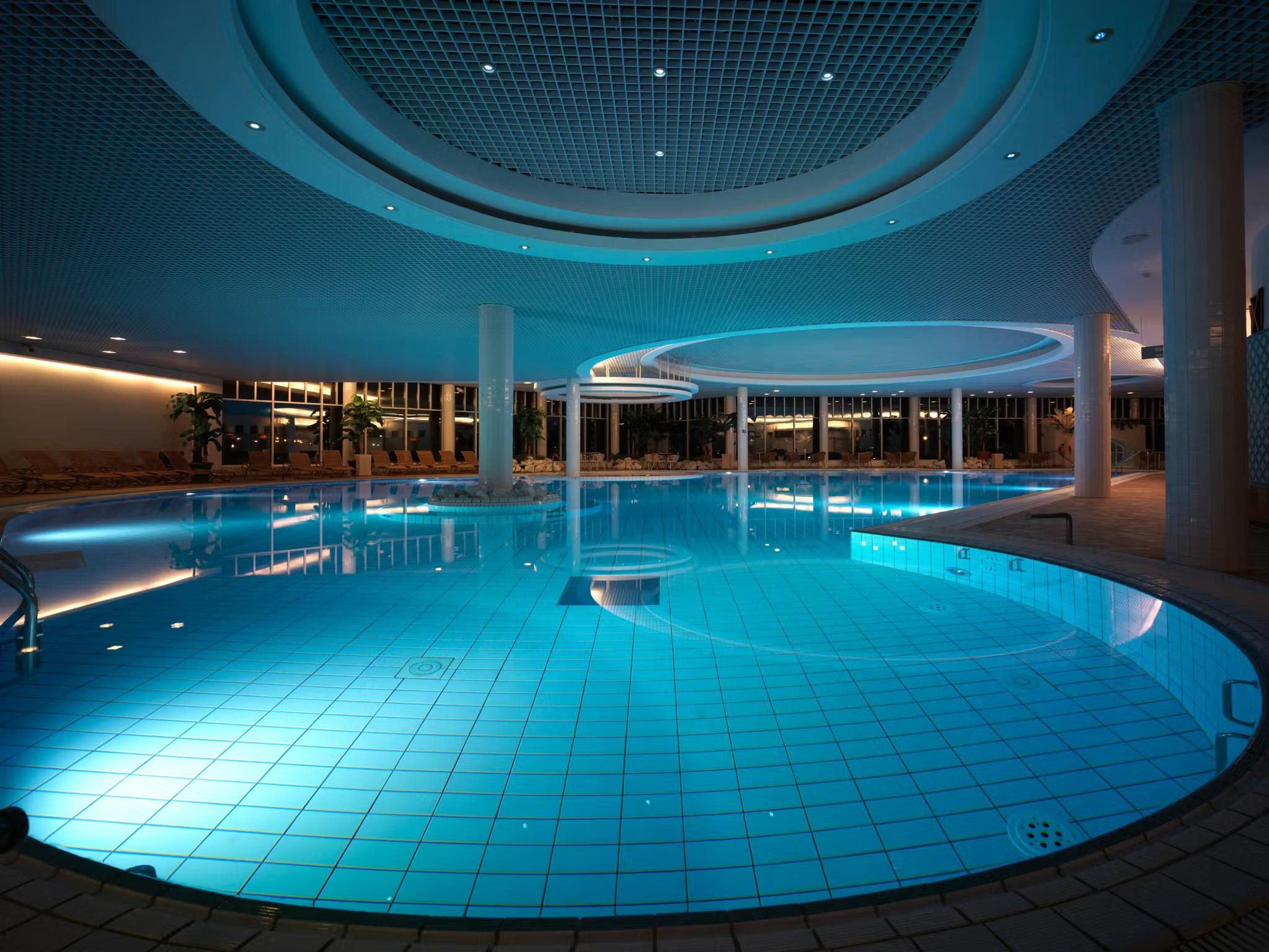 En stor, moderne indendørs swimmingpool med blåbelyst vand.